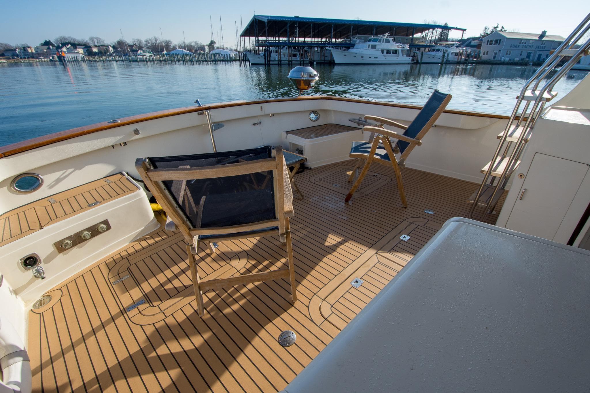 Deck of 2000 Fleming 55 yacht with chairs, overlooking marina.