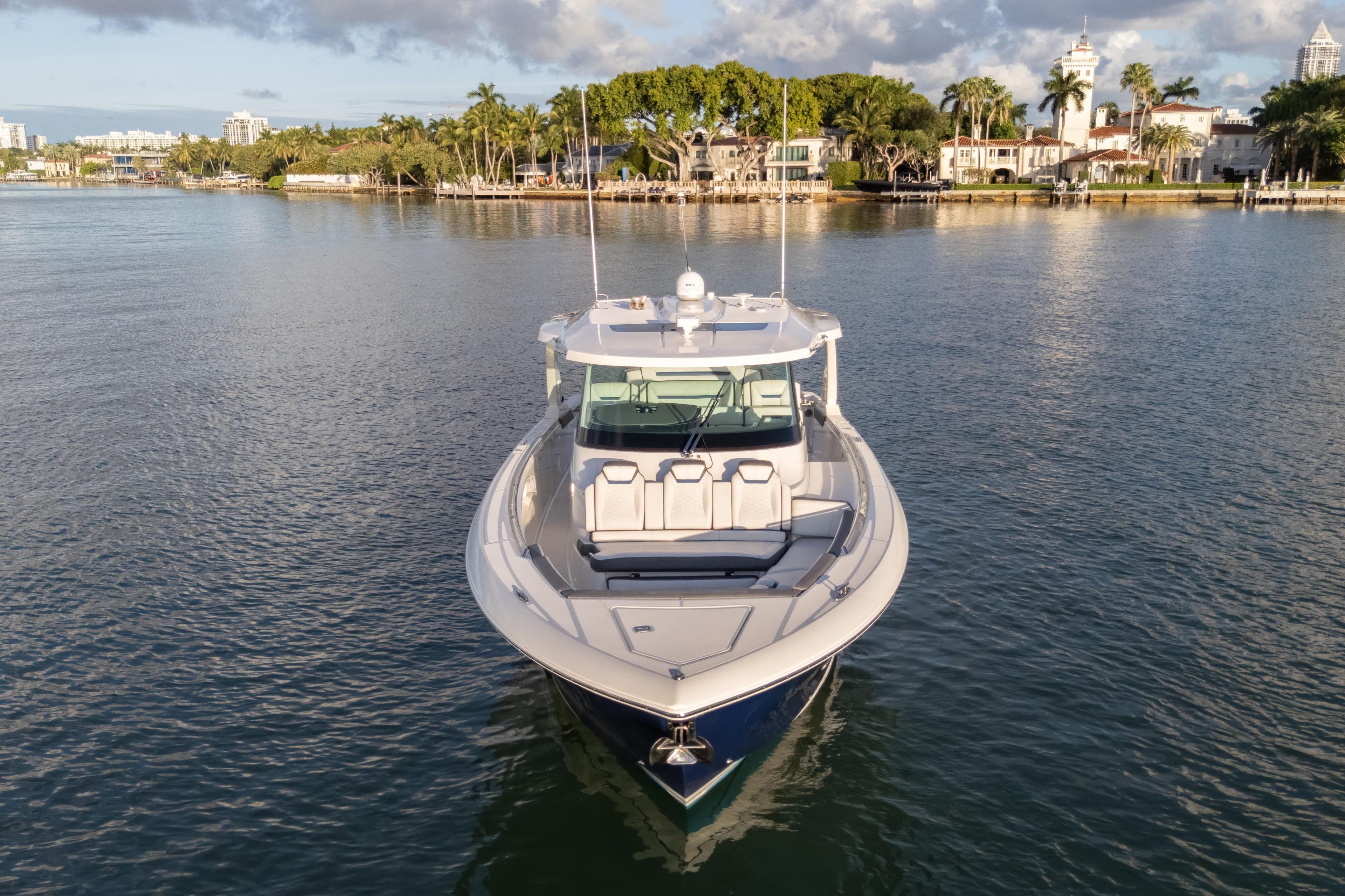 2020 Tiara Yachts 43 LS on calm water, surrounded by lush greenery and luxury homes.