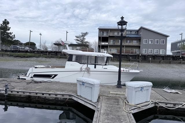 2016 Jeanneau Merry Fisher 855 Marlin docked at a marina with overcast skies.
