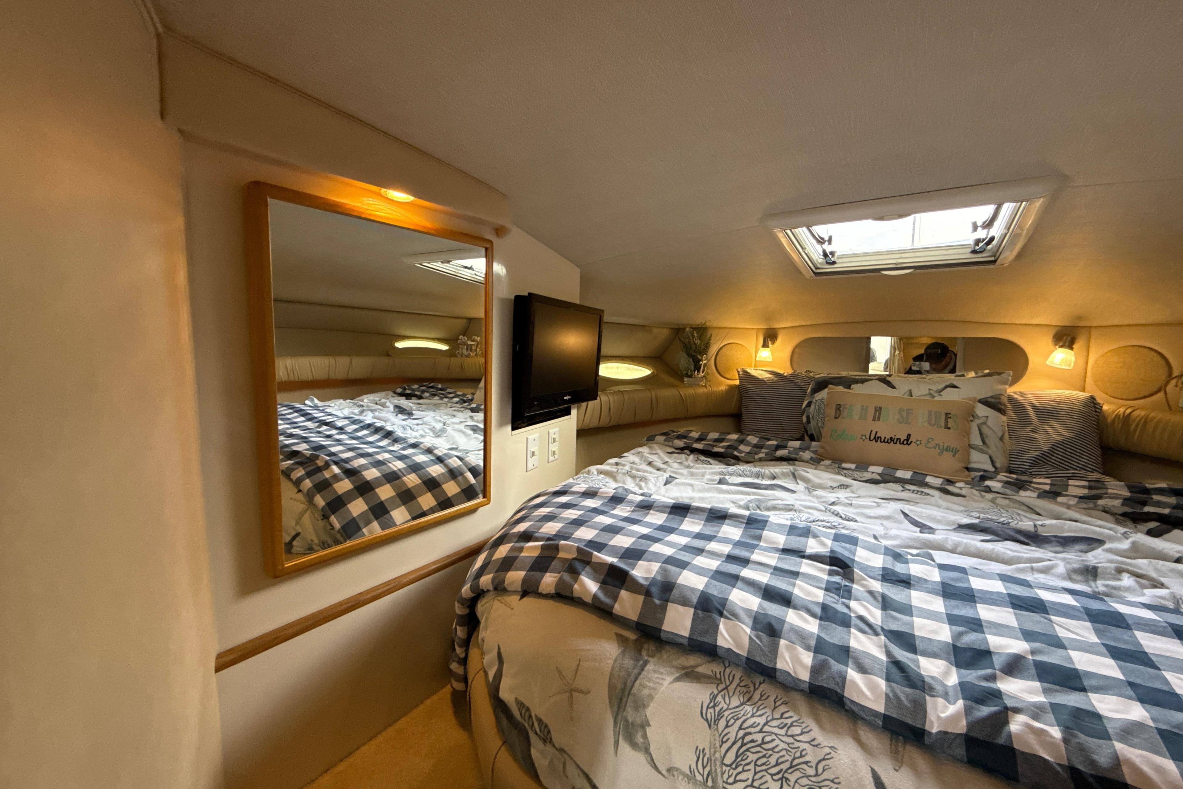 Cozy cabin interior of 1995 Sea Ray Sundancer 370 with bed, mirror, and skylight.