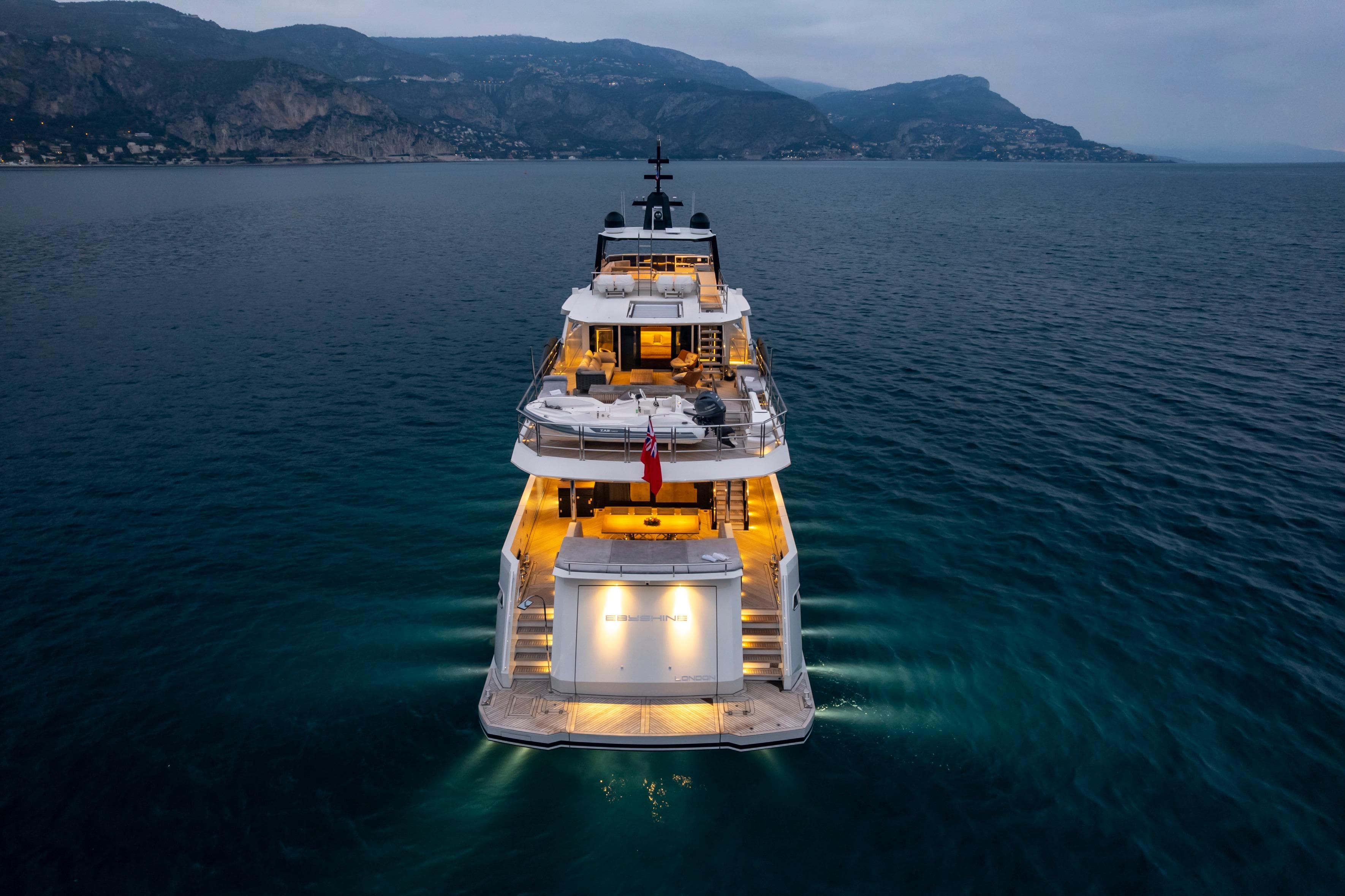 Luxurious Blaundus V30 Explorer yacht illuminated at dusk on serene waters, 2023 model.