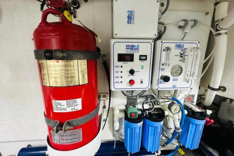Engine room equipment on a 2017 Cruisers Yachts 60 Fly, featuring a fire extinguisher and control panels.