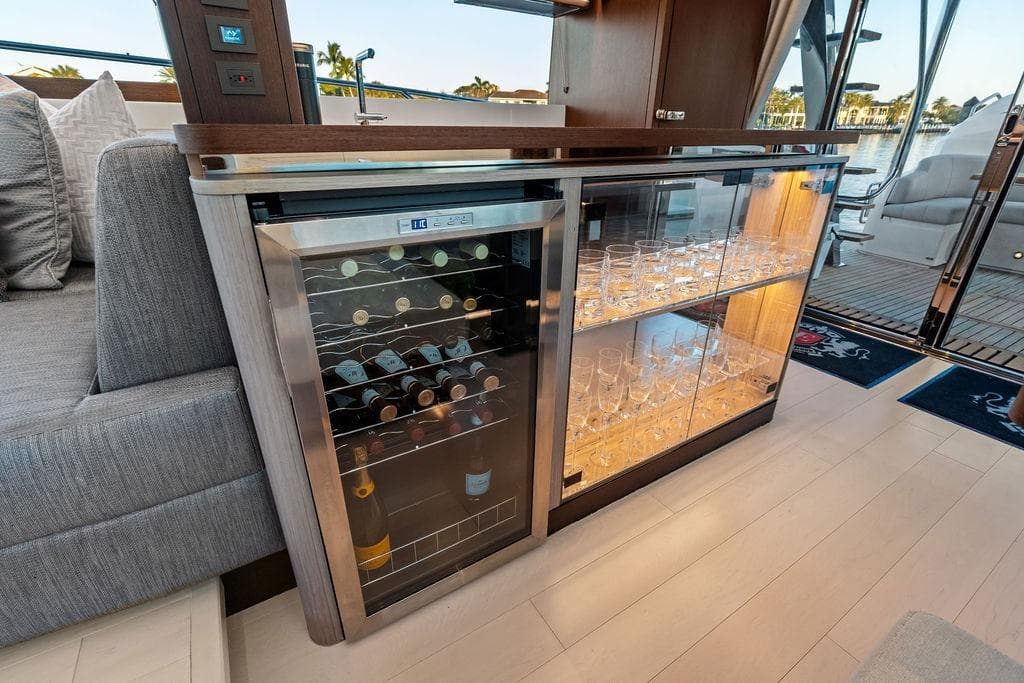 Luxurious interior of 2021 Sunseeker Manhattan 68 yacht with wine cooler and glass cabinet.