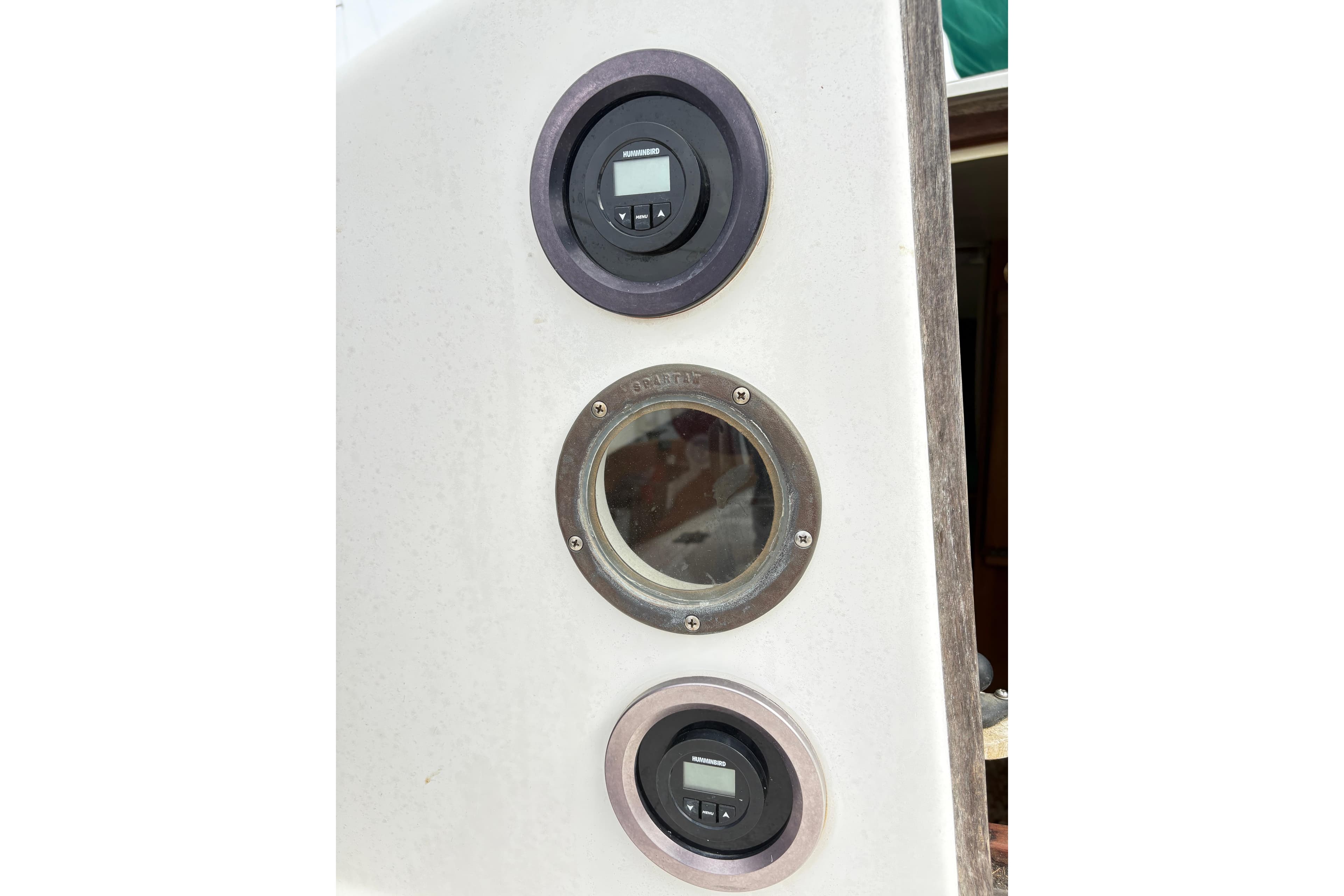 Control panel on a 1986 Cape Dory 26 sailboat with gauges and porthole.