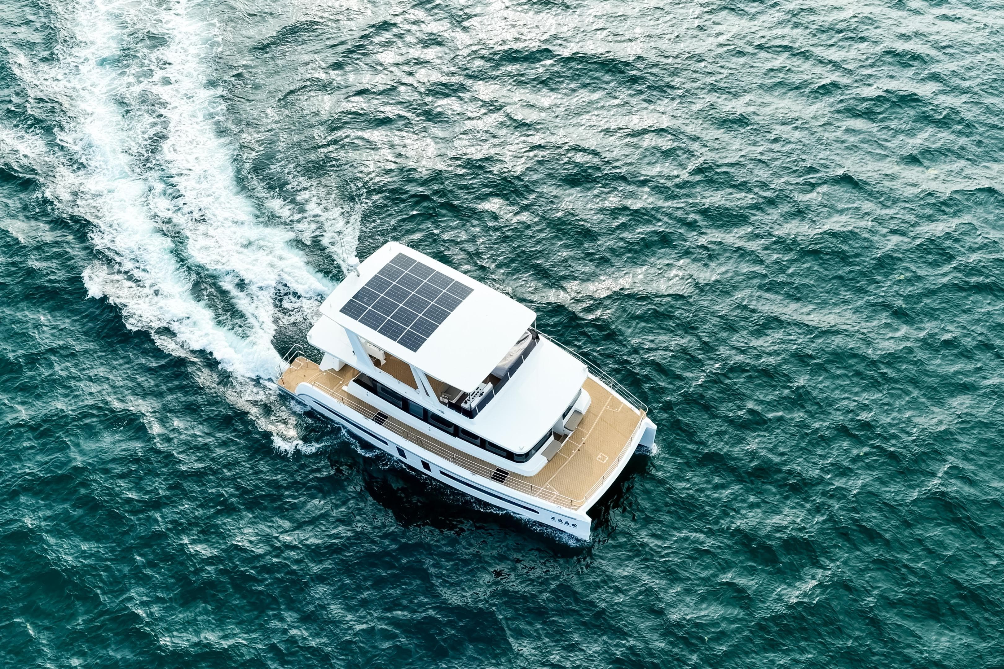 Aerial view of 2025 Mazarin 55 Catamaran with solar panels cruising on the ocean.