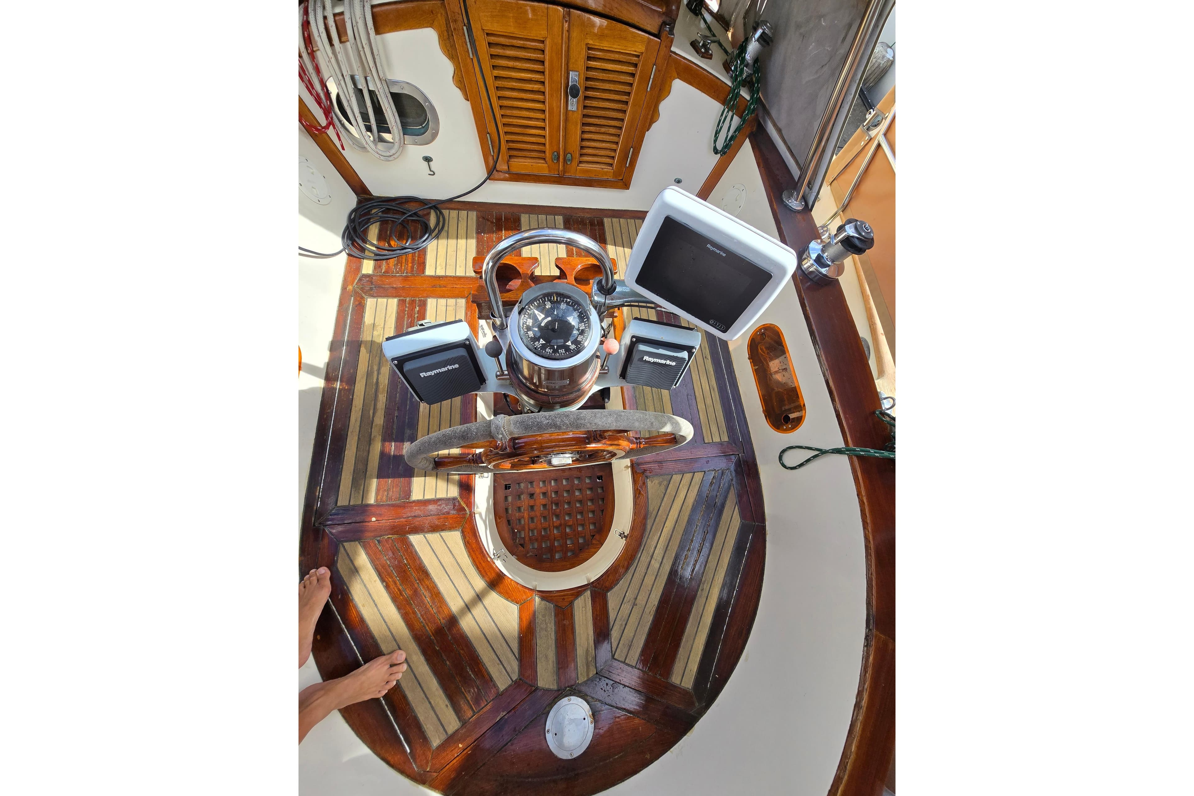 Cockpit of 1985 Baba 35 sailboat with wooden wheel and navigation equipment.