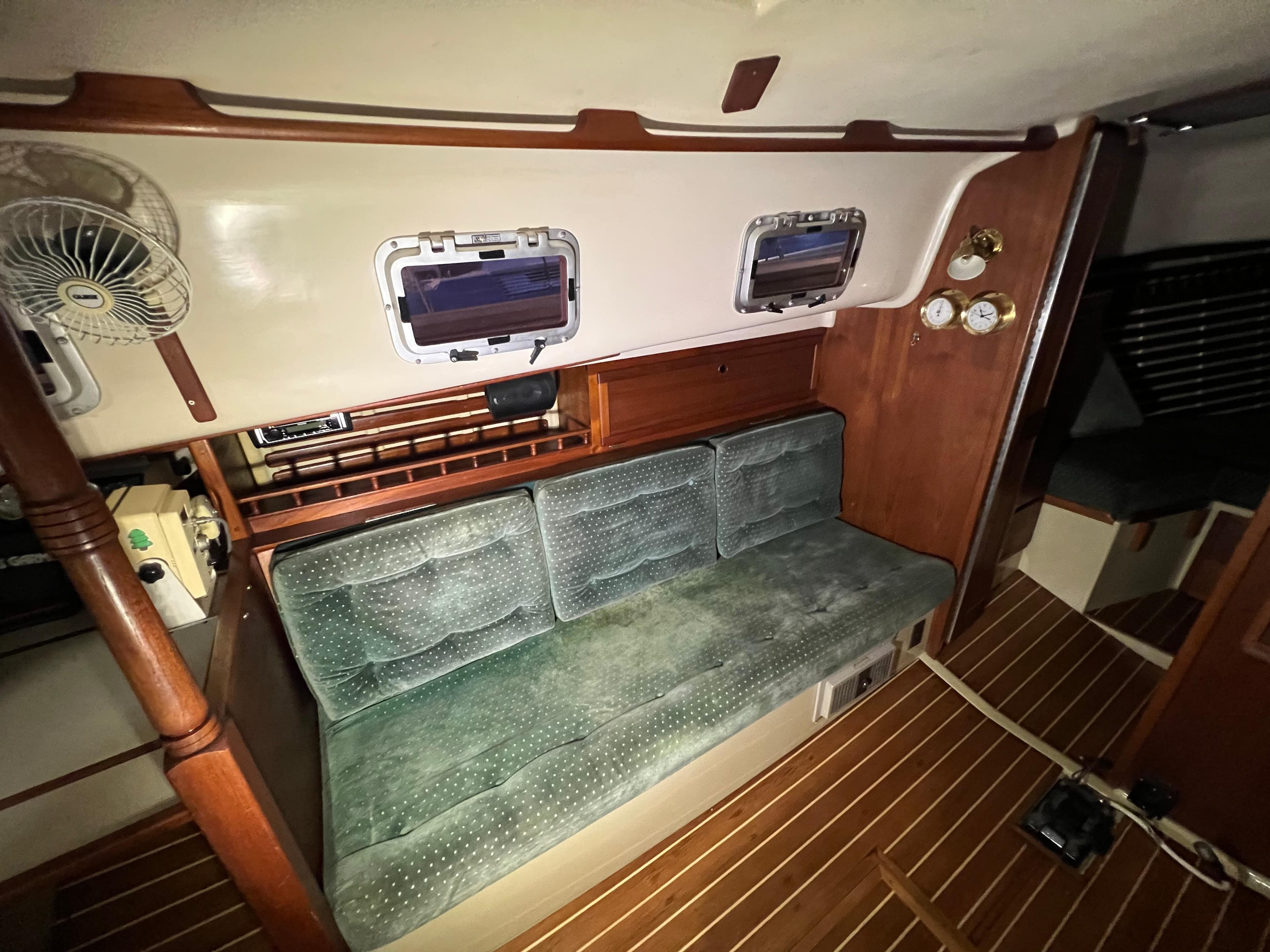 Interior of 1987 Bayfield 32C sailboat with green cushioned seating and wooden accents.