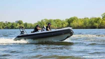 2024 Grand Inflatables S420 boat cruising on a lake with two passengers.