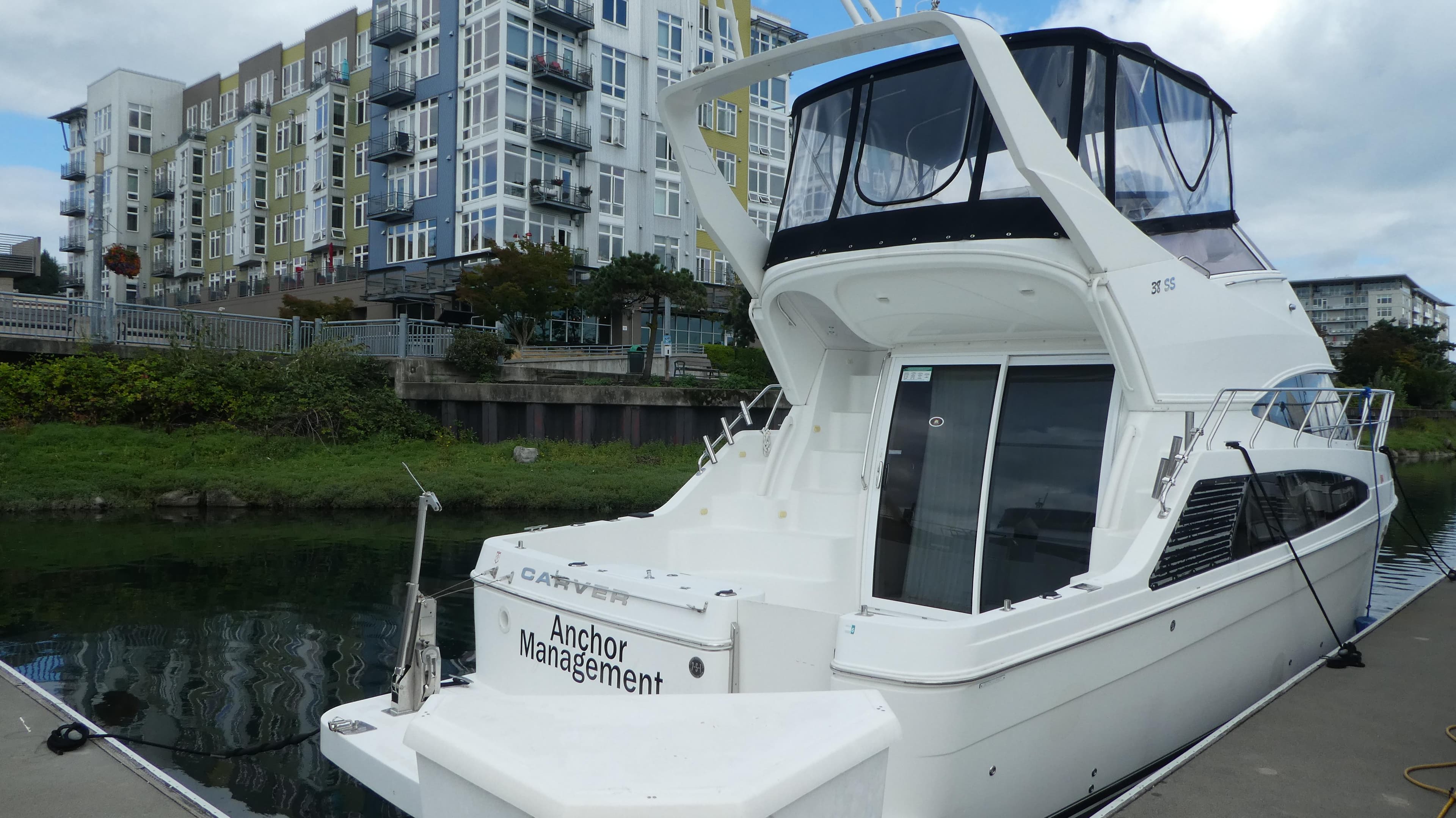 2005 Carver 38 Super Sport yacht docked near modern apartments.