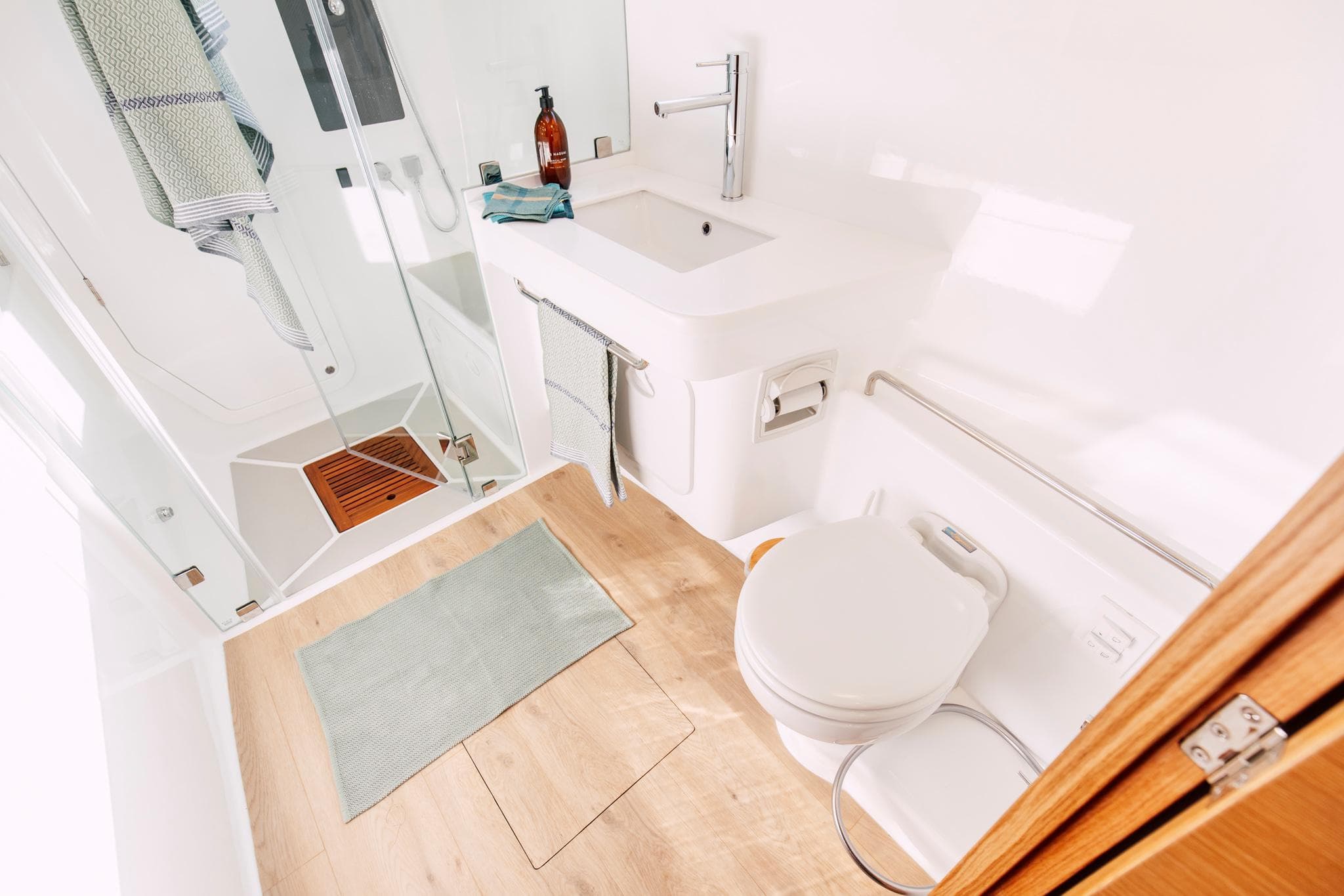 Modern bathroom in Vision 444 model, 2026, featuring shower, sink, and toilet with wooden accents.