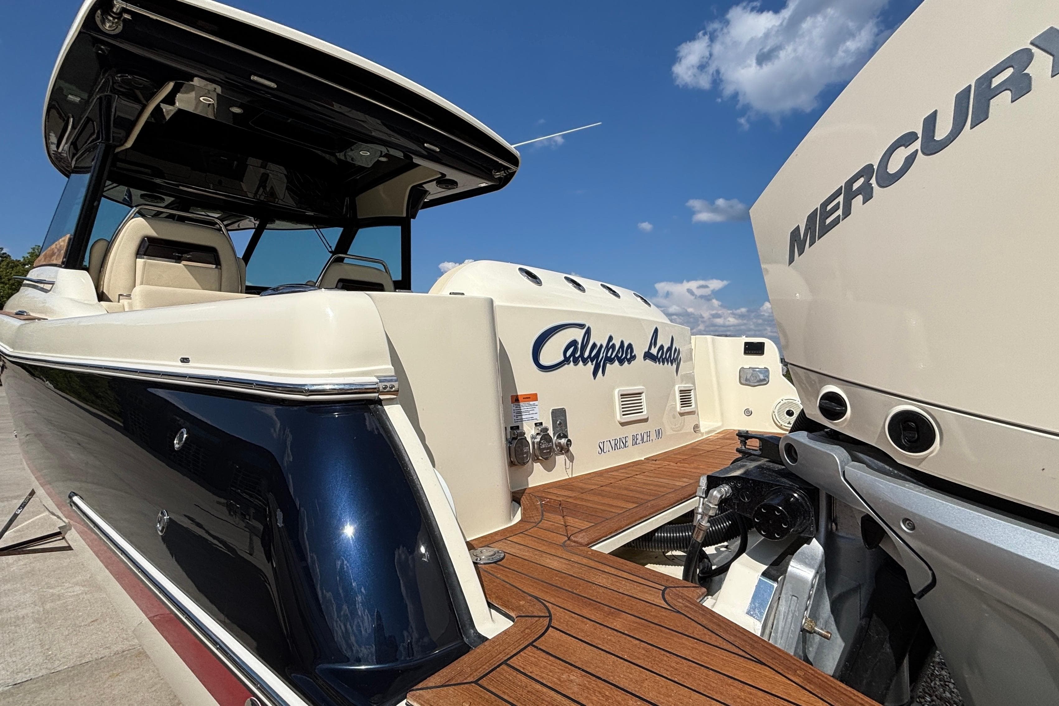 2021 Chris-Craft Calypso 35 boat with Mercury engine, docked under clear blue sky.