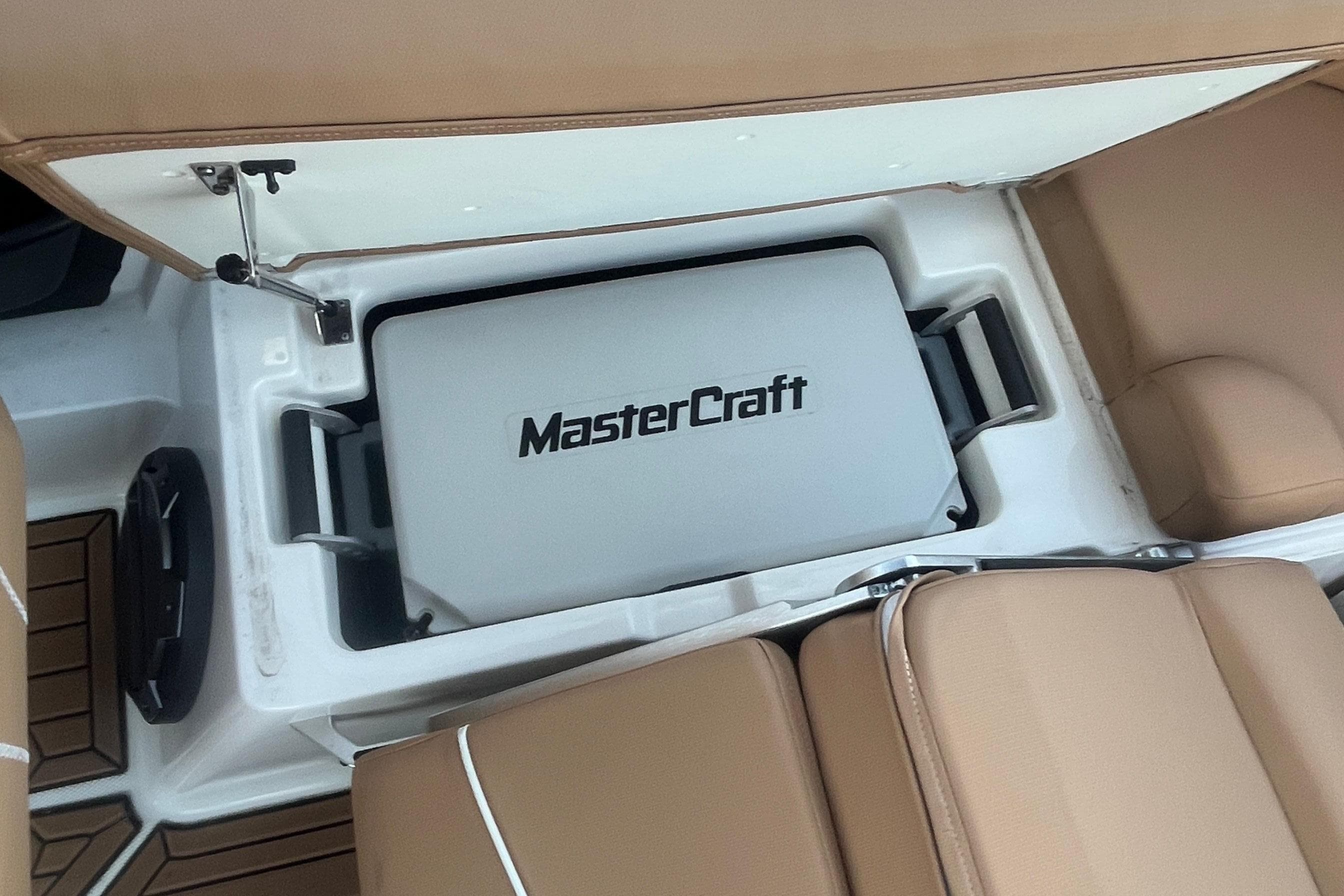 2021 MasterCraft XT21 boat interior with storage compartment and tan seating.
