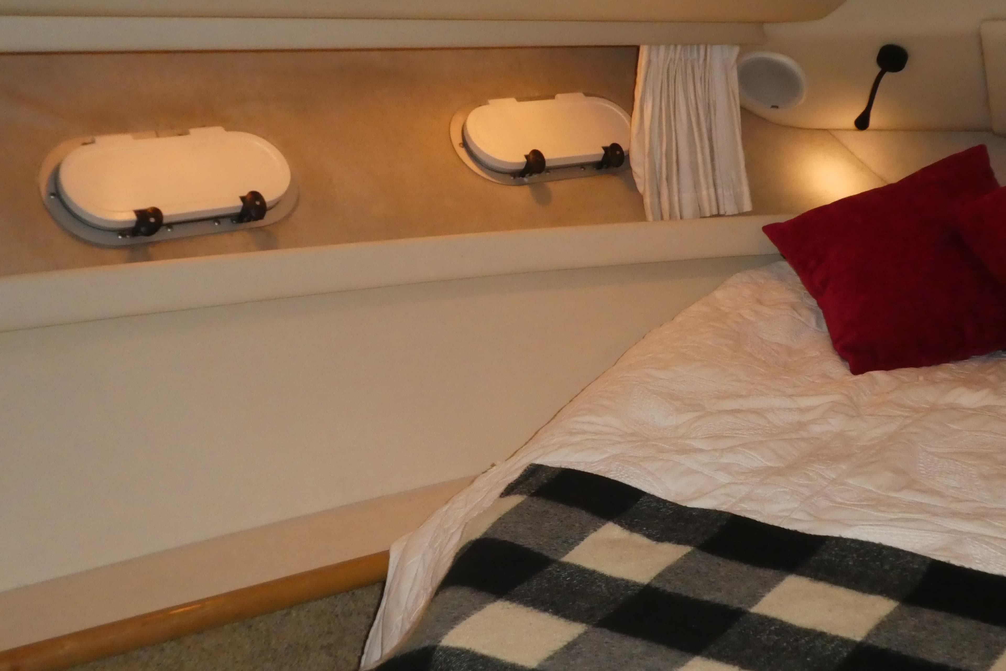 Cozy bedroom interior of 1994 Bayliner 4388 Motor Yacht with portholes and bedding.
