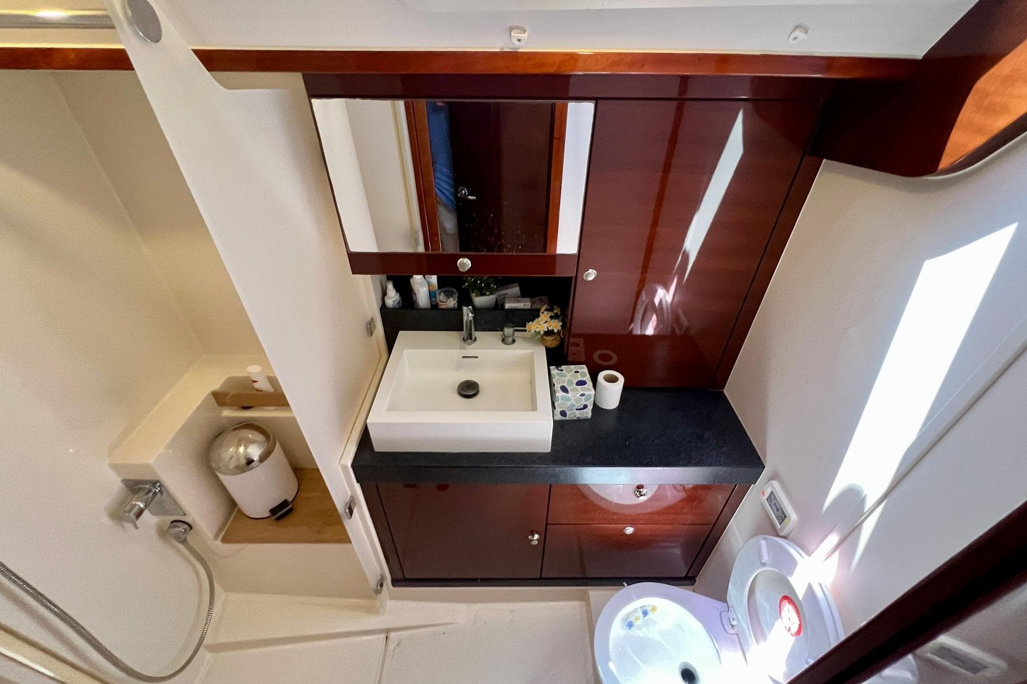 Luxurious bathroom interior of 2010 Hanse 630e yacht with modern sink and wooden cabinetry.