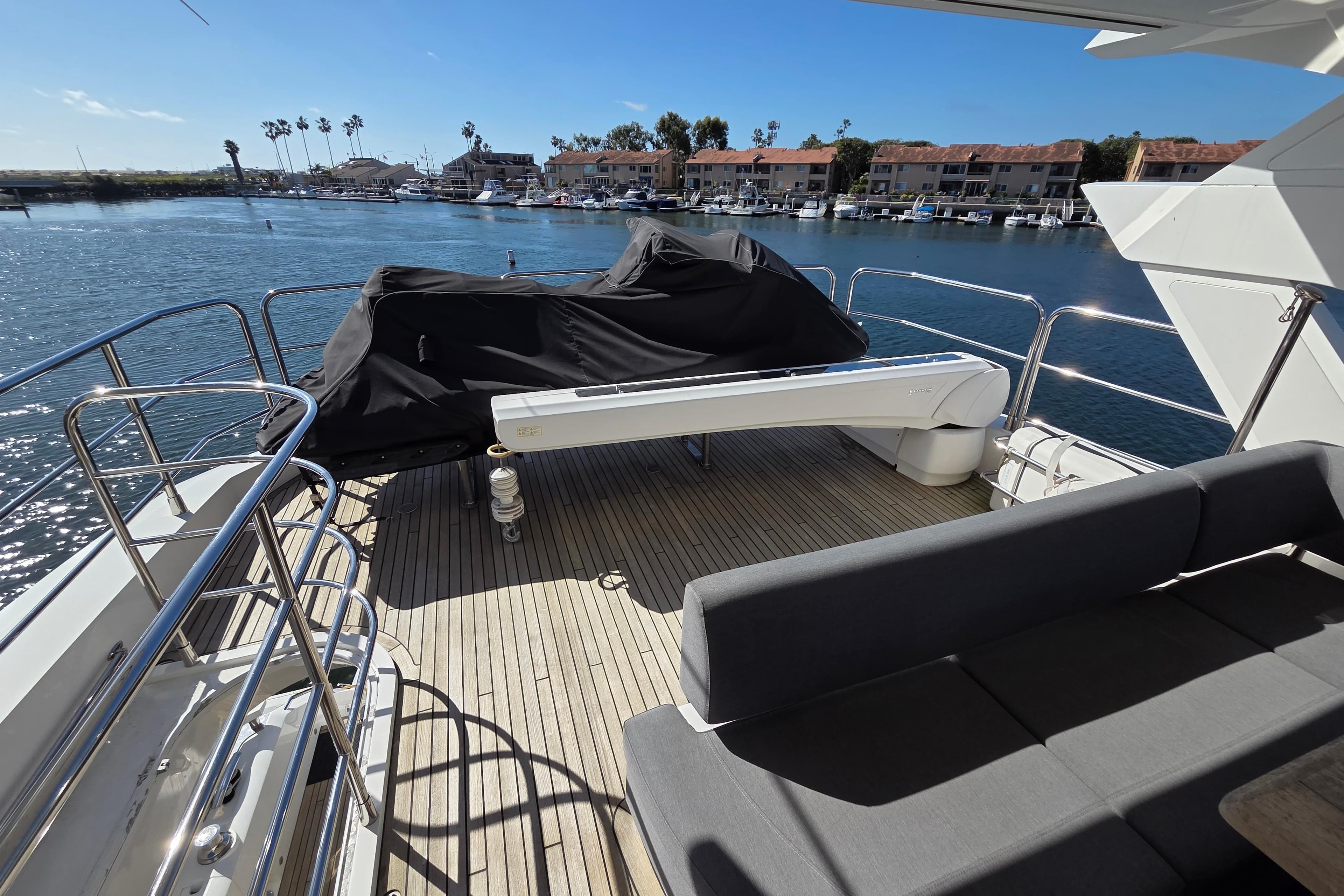 Sunseeker 76 Yacht 2018 deck with covered equipment, overlooking marina and waterfront homes.