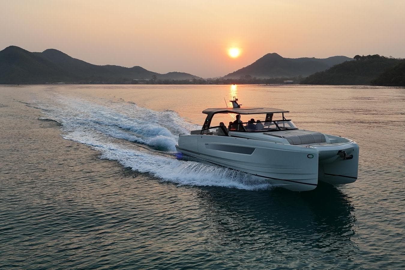 2025 YOT Yot 36 cruising at sunset on serene waters with mountains in the background.