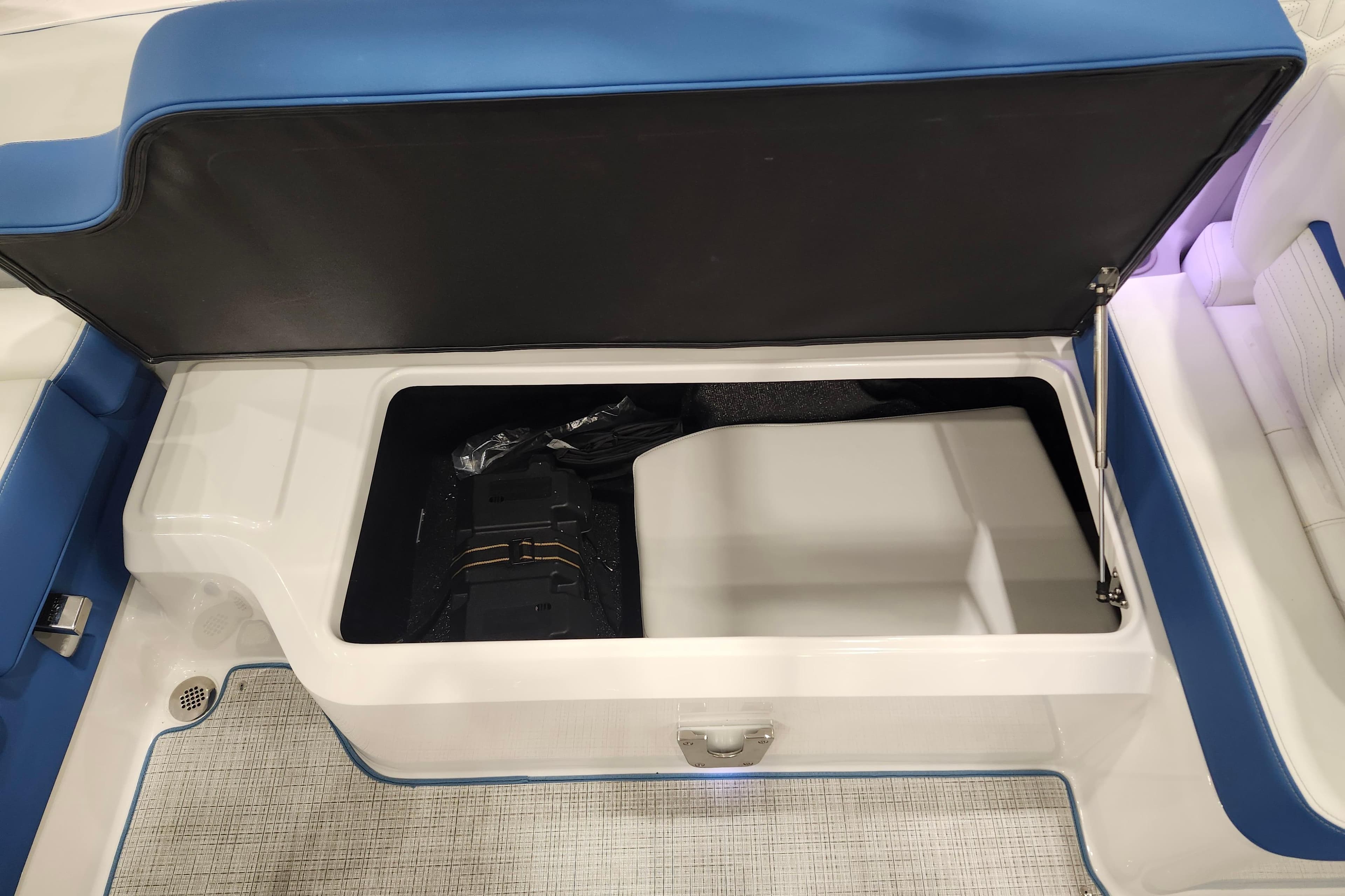 Open storage compartment in 2026 Regal LS6 Surf boat with blue seating.