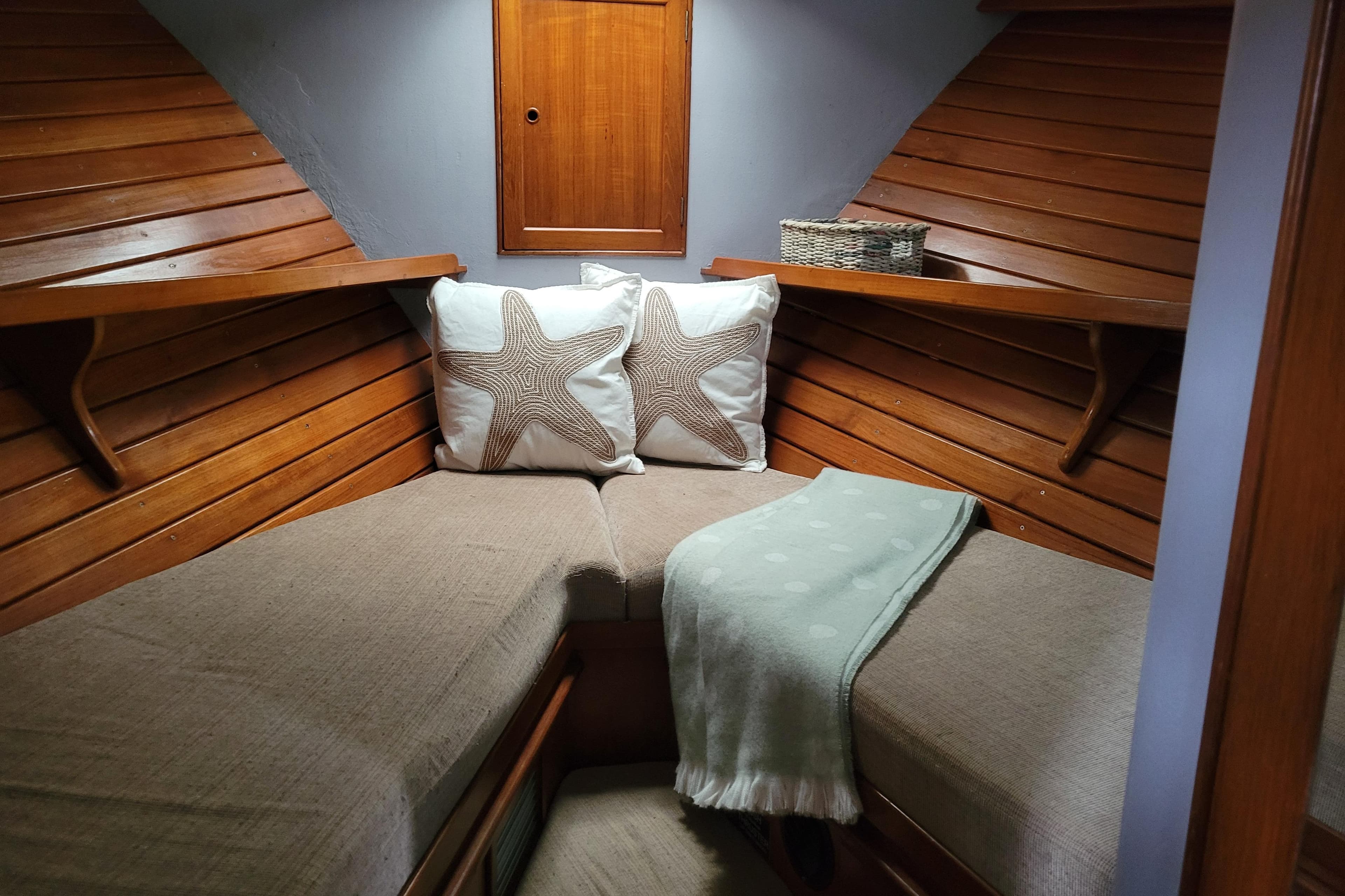 Cozy cabin interior of 1982 Kong & Halvorsen Island Gypsy with starfish pillows and wooden paneling.