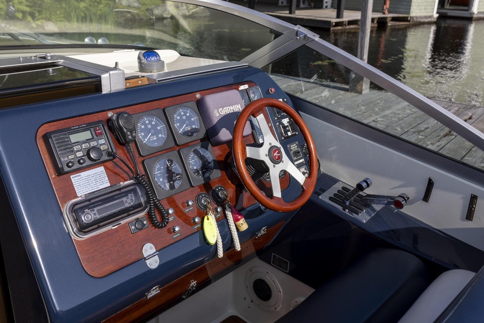 Control panel of a 1997 Kavalk 30 boat with wooden steering wheel and gauges.