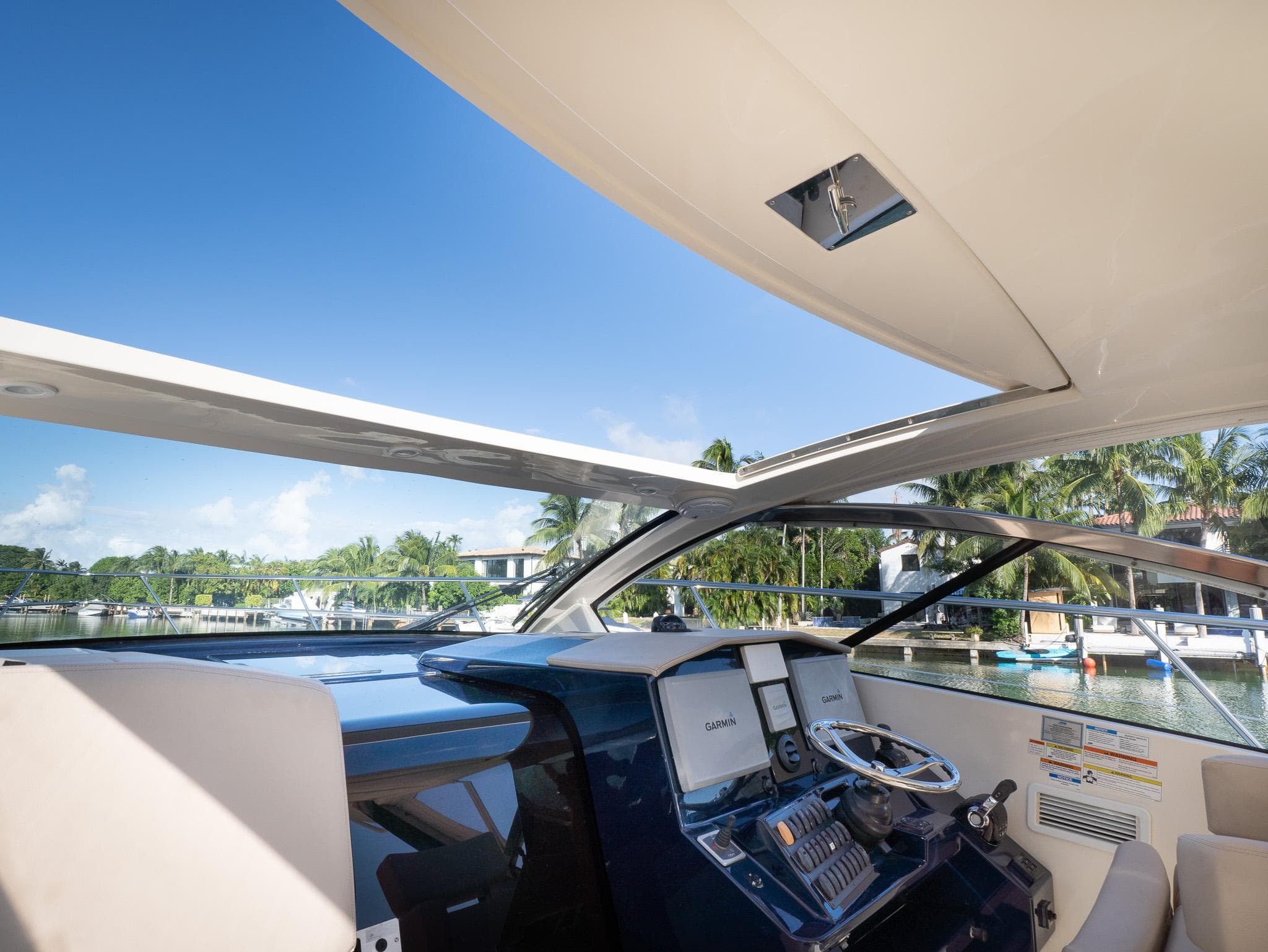 2014 Pursuit SC 365i Sport Coupe helm with open roof, showcasing marina view.