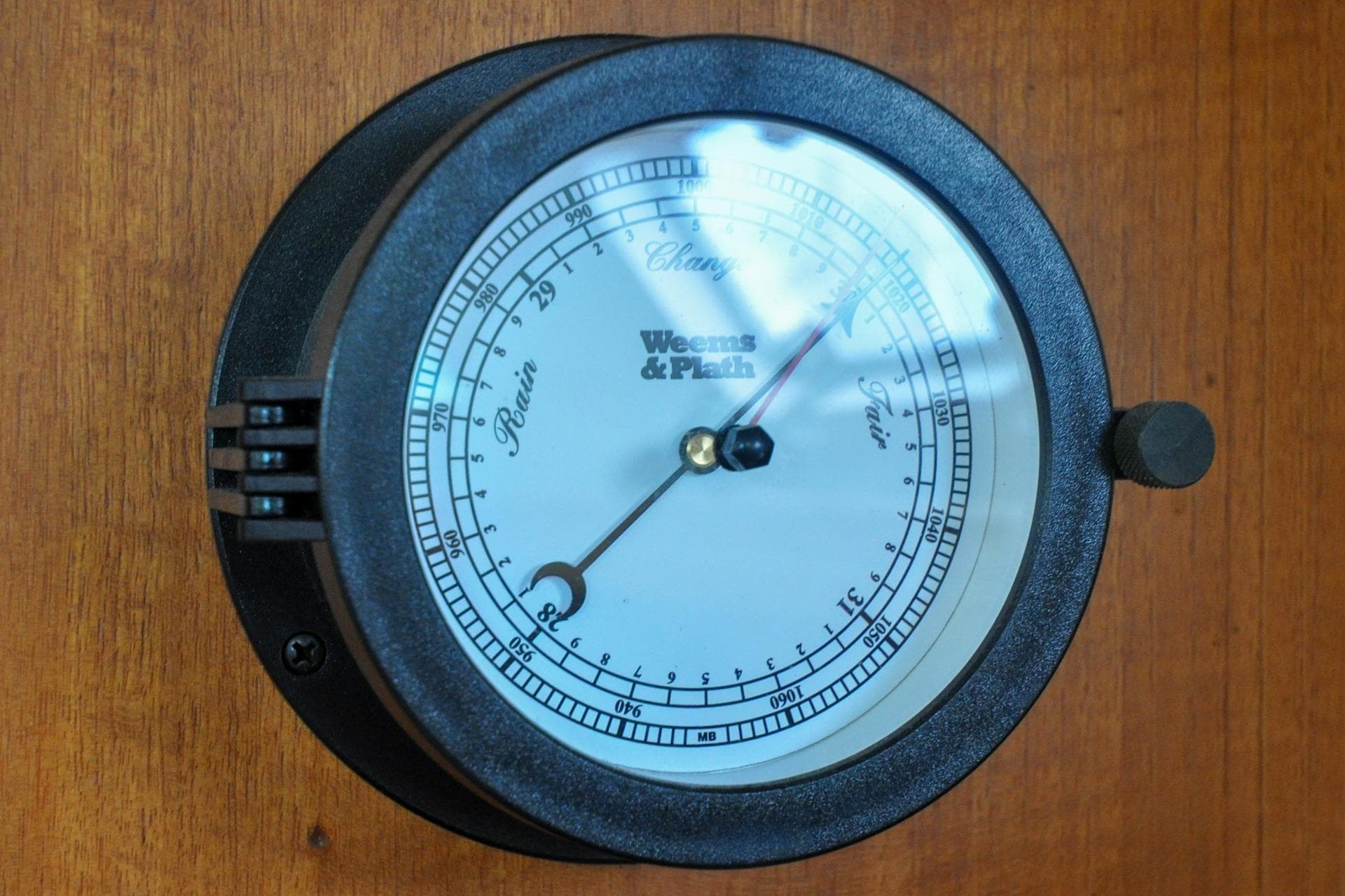 Barometer on 1993 Catalina 42 yacht, displaying atmospheric pressure, mounted on wooden panel.