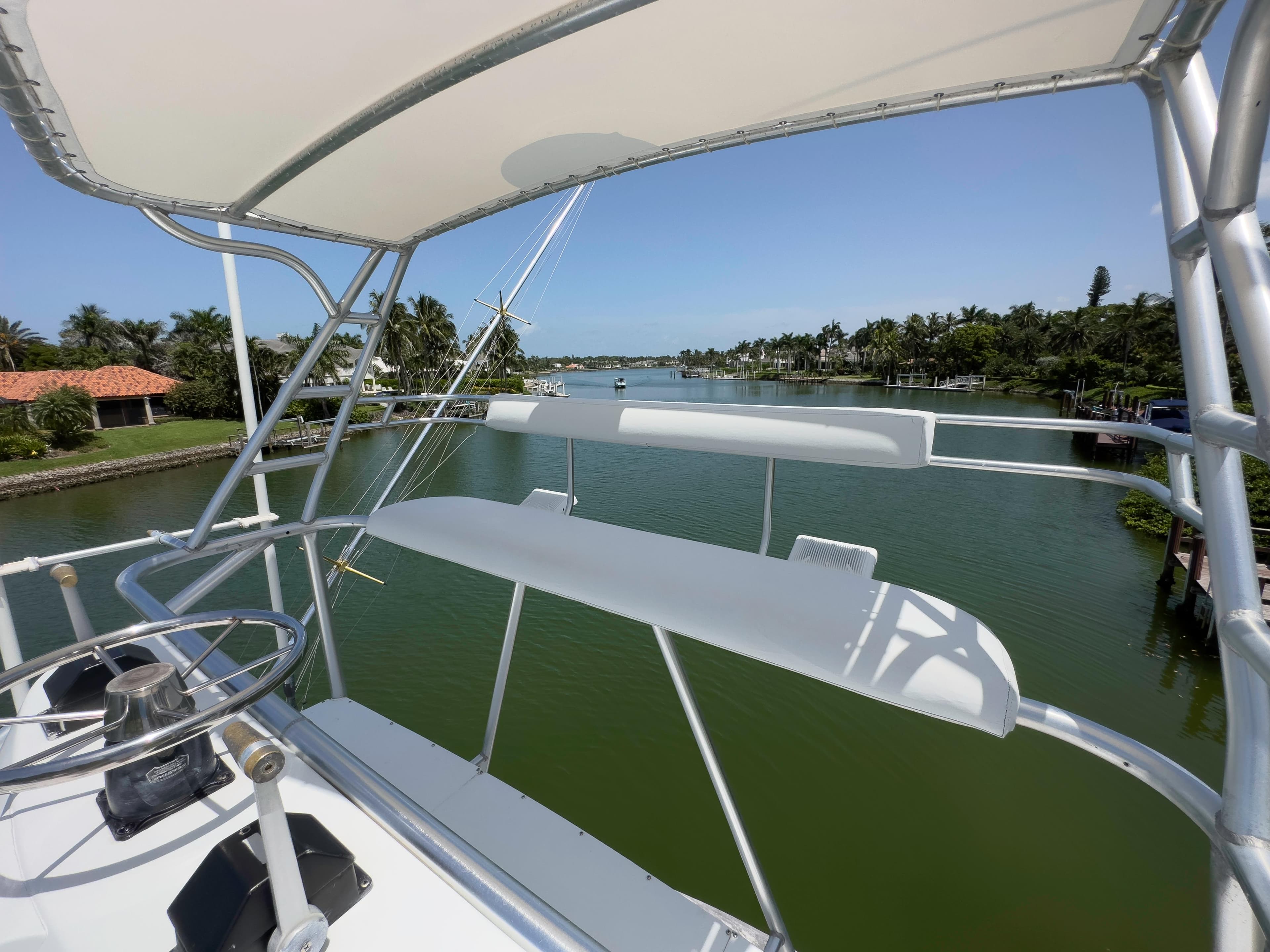View from the helm of a 1990 Buddy Davis 61 Convertible yacht on a serene waterway.
