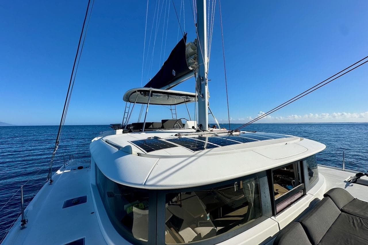 2023 Lagoon 46 catamaran sailing on open sea under clear blue sky.