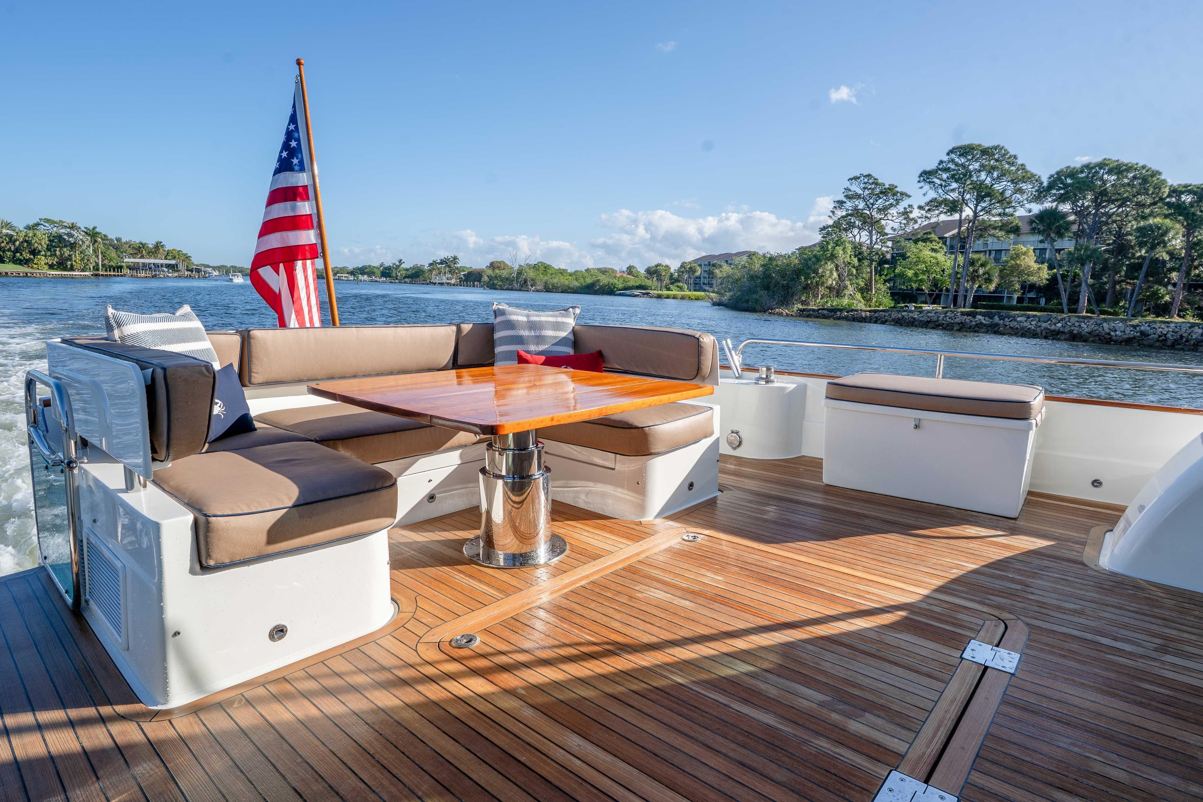 Luxurious 2018 Sabre 66 Dirigo yacht deck with seating, table, and American flag.