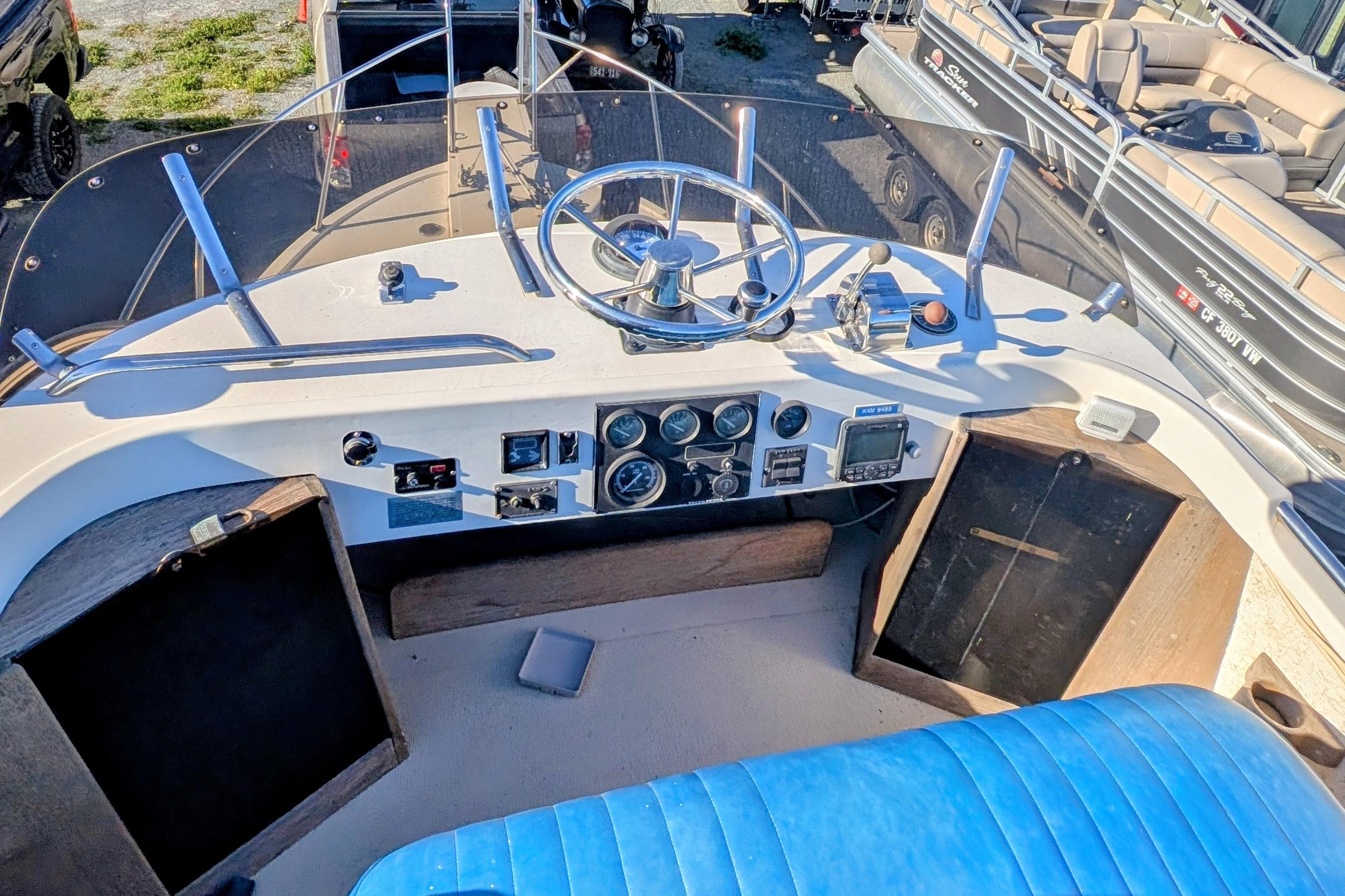 1989 Blackman Billfisher 26 boat cockpit with steering wheel, gauges, and blue seating.
