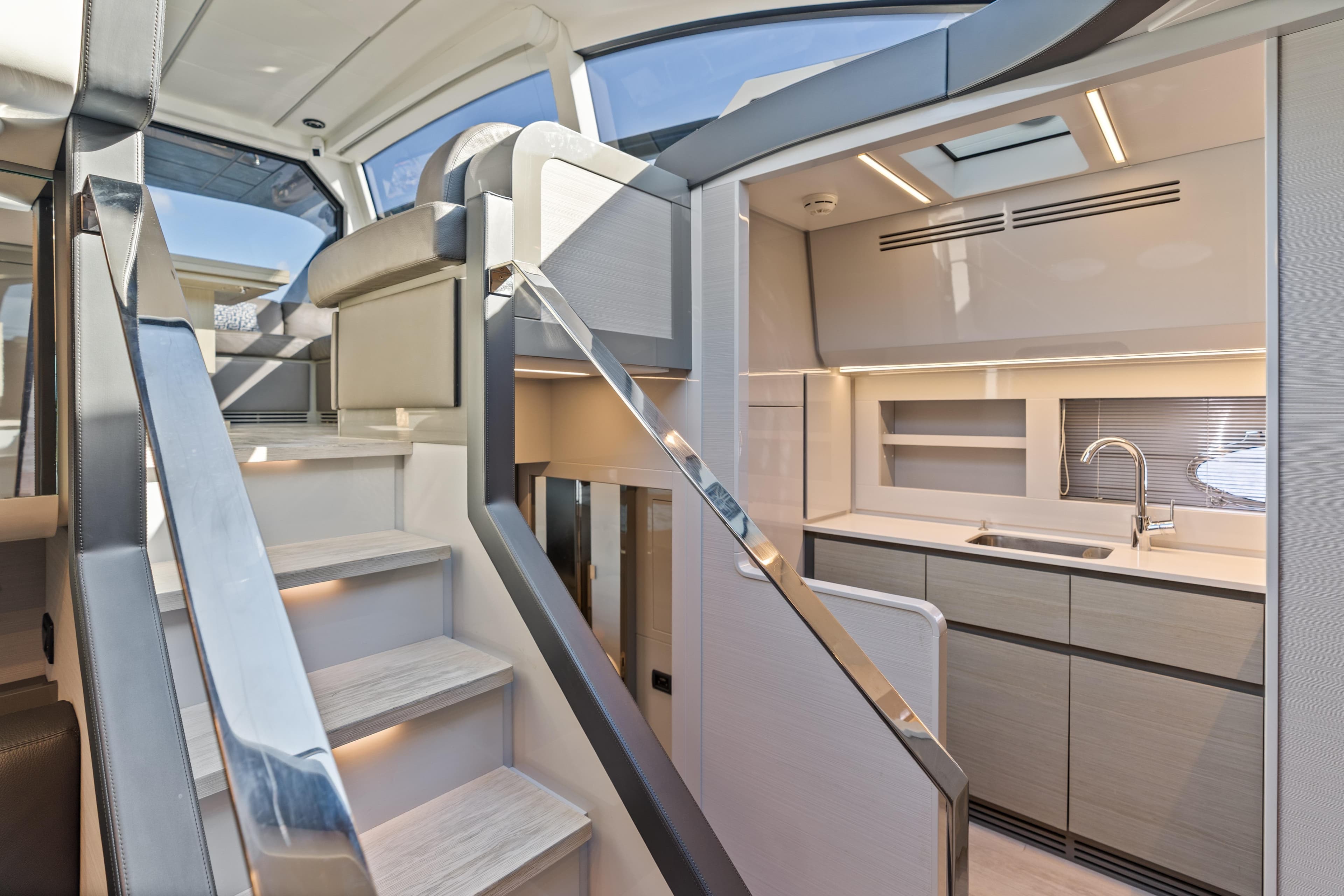 Luxurious interior of 2016 Pershing 62' yacht with modern kitchen and sleek staircase.
