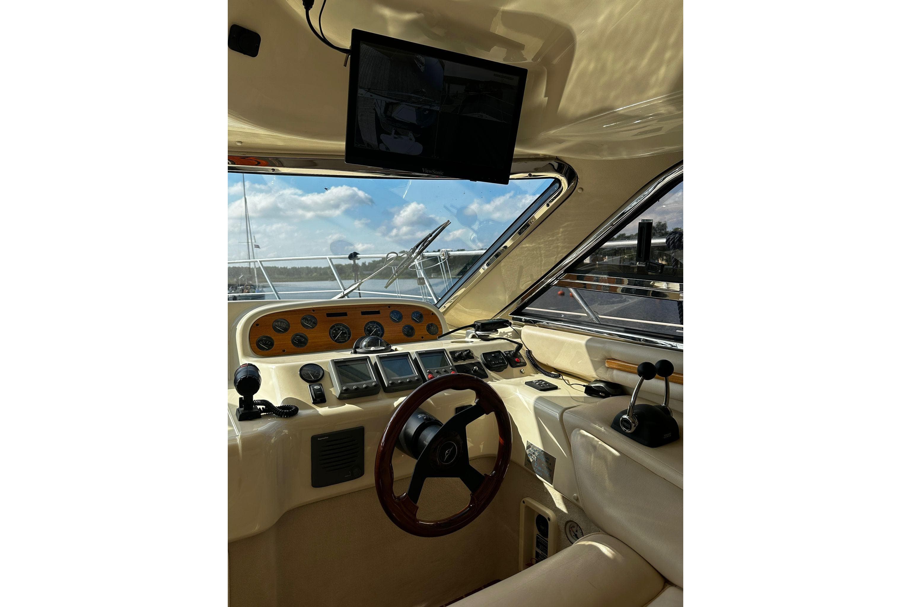 Interior view of 2006 Sealine F43 yacht cockpit with steering wheel and control panel.