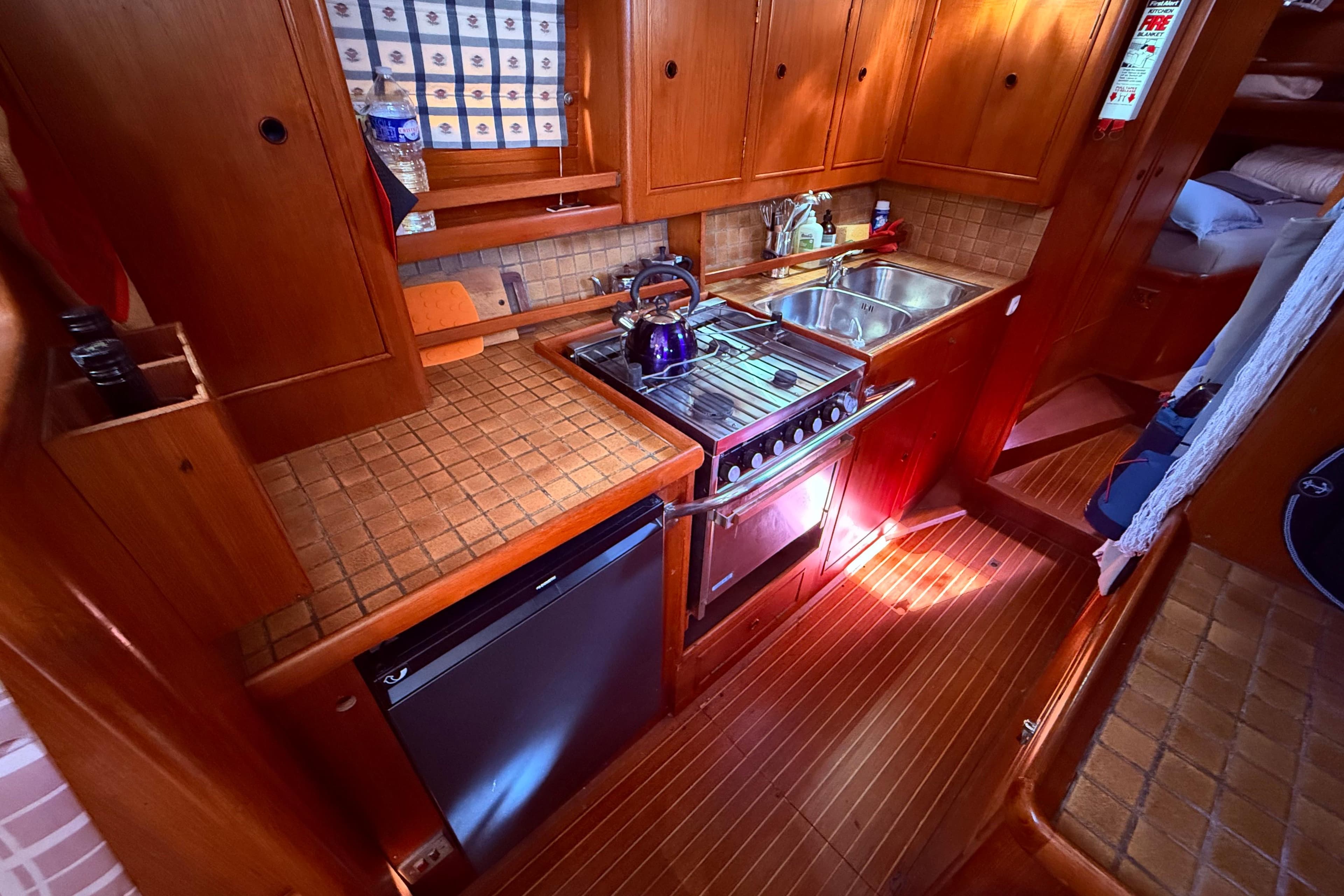 Compact kitchen in 1983 Moody 134 Grenadier yacht with wooden cabinetry and modern appliances.