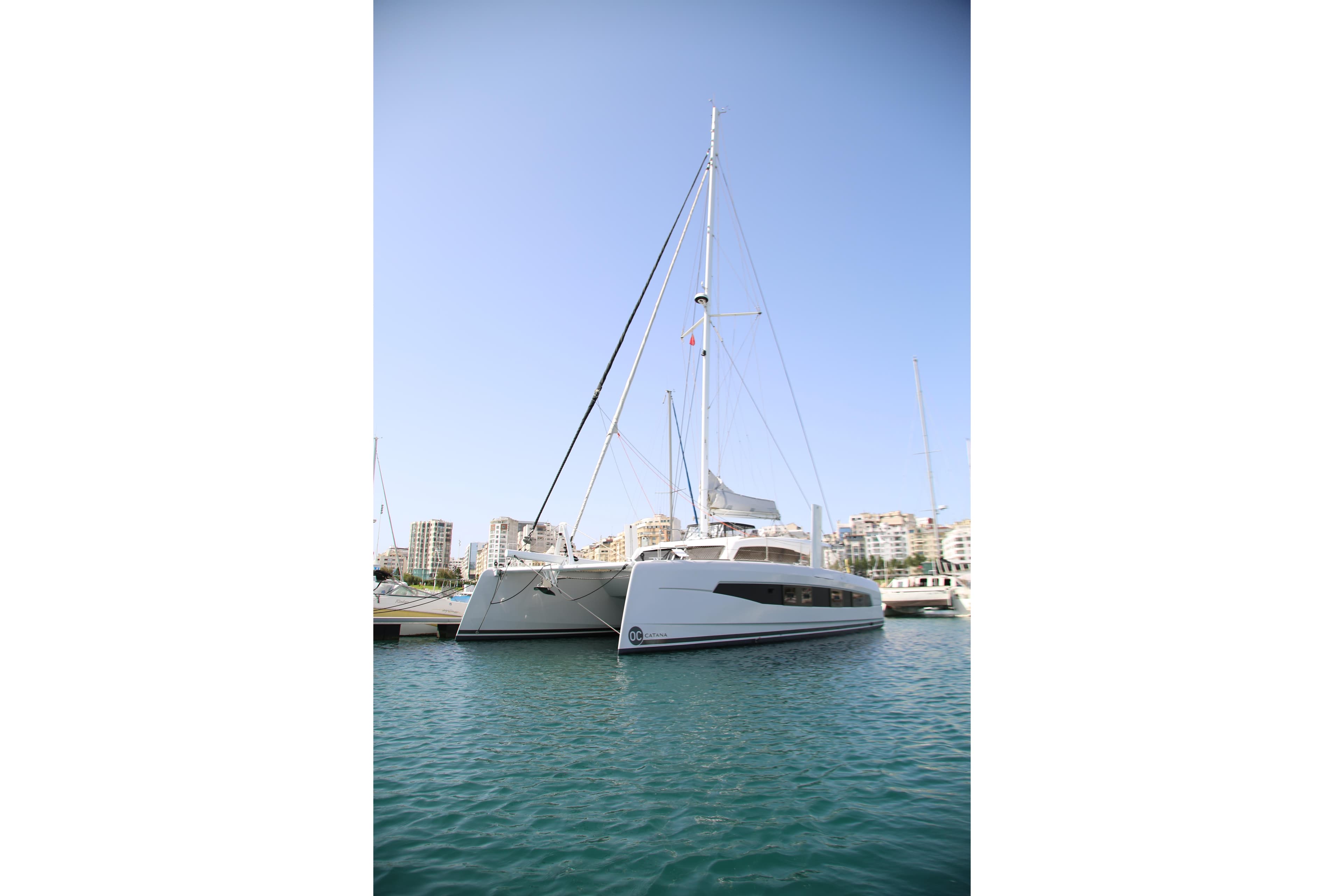 2023 Catana OC 50 catamaran docked in a marina, clear blue sky background.