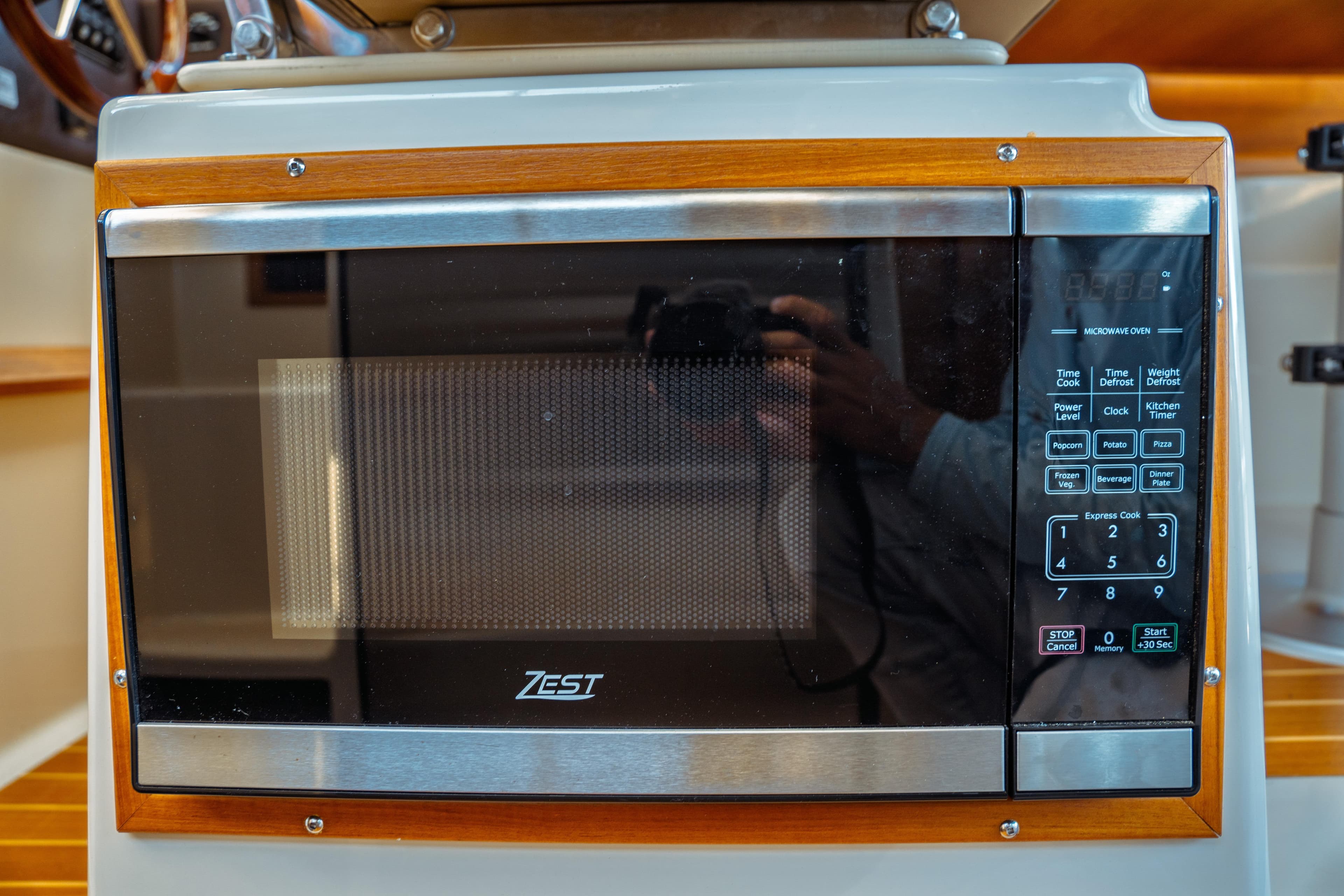 Microwave oven in 2022 Ranger Tugs R-29 S boat interior, featuring wood trim and digital controls.