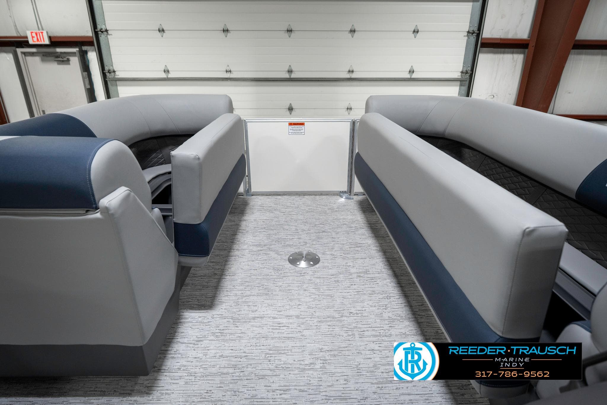 2025 Bennington 22 SLS boat interior with gray and blue seating in a showroom.