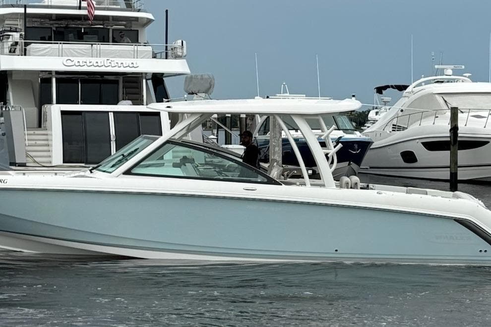 2017 Boston Whaler 320 Vantage boat docked near luxury yachts in a marina.