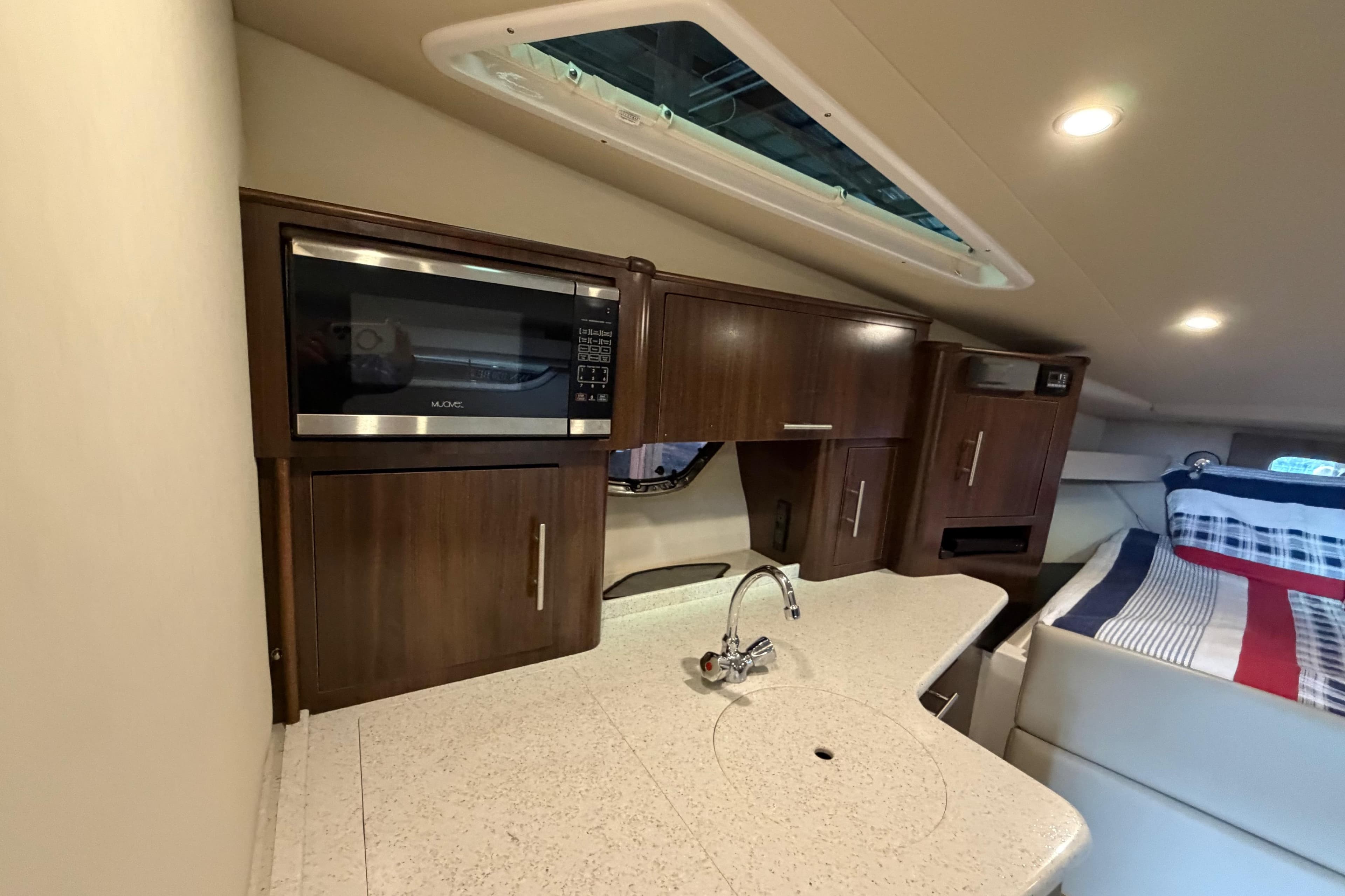 Interior of 2016 Regal 35 Sport Coupe featuring kitchenette and cozy sleeping area.