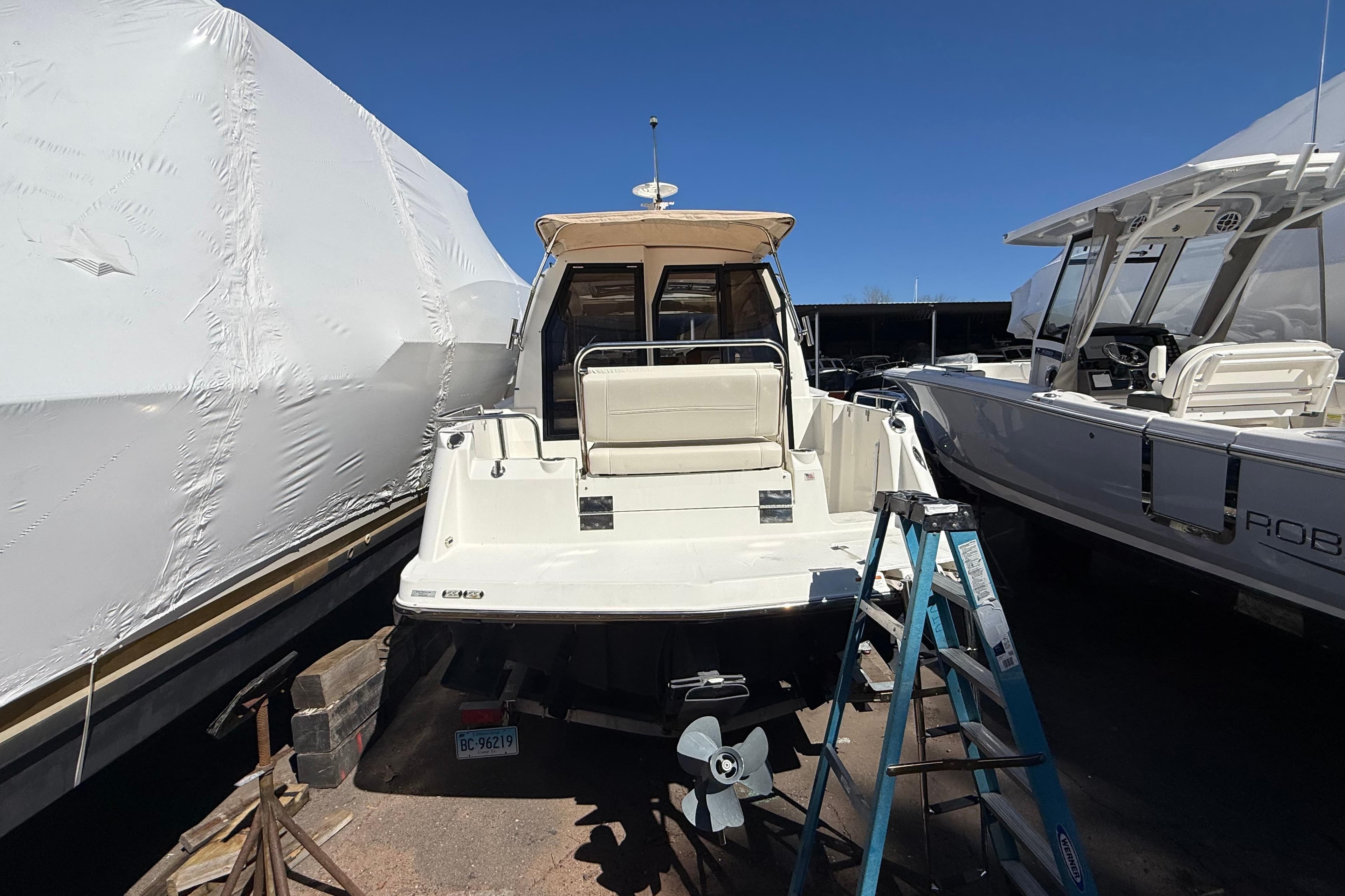 2016 Cutwater 24 boat in storage, surrounded by other boats, with a ladder nearby.