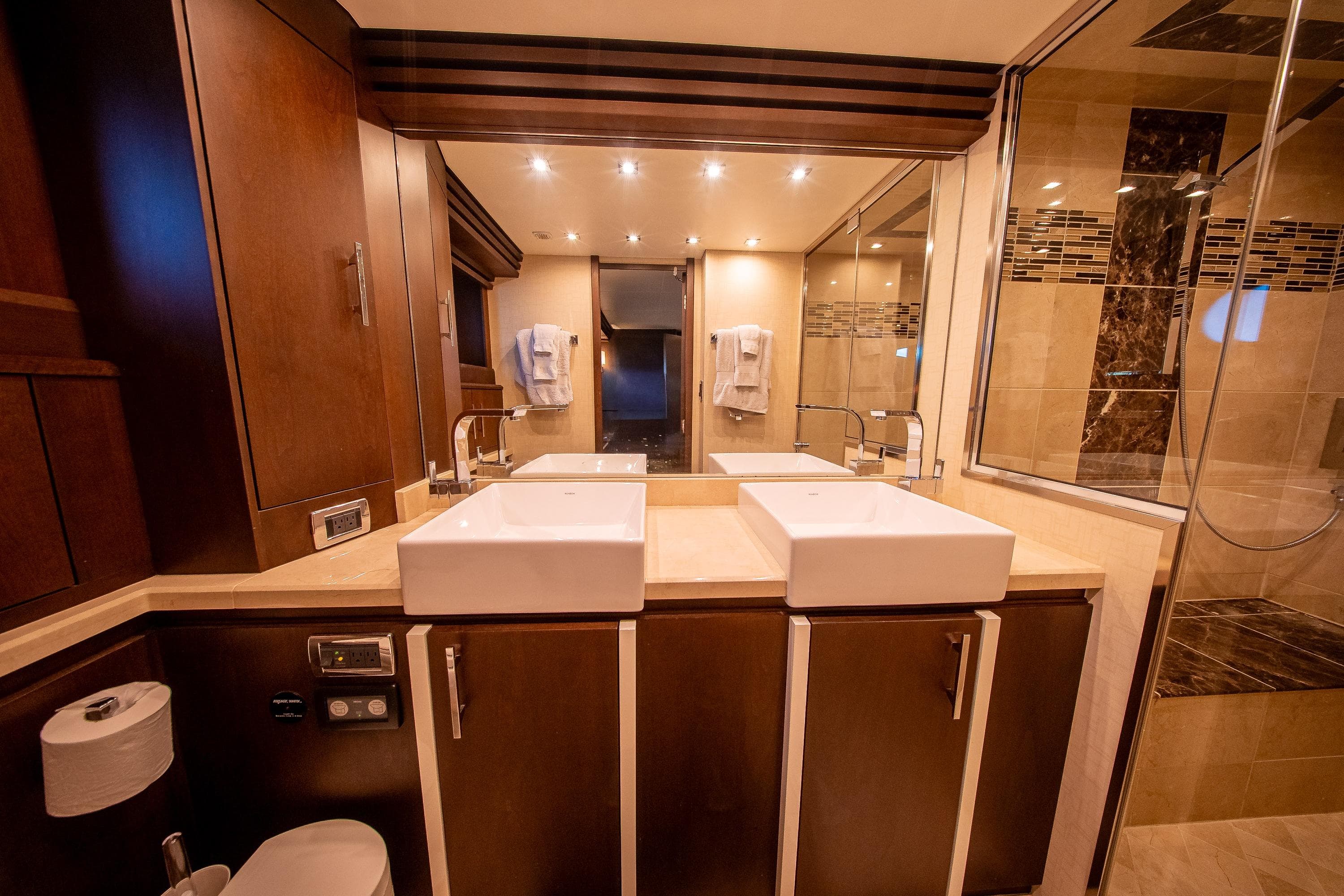 Luxurious bathroom in 2012 Marquis 690 yacht with dual sinks and elegant wood cabinetry.