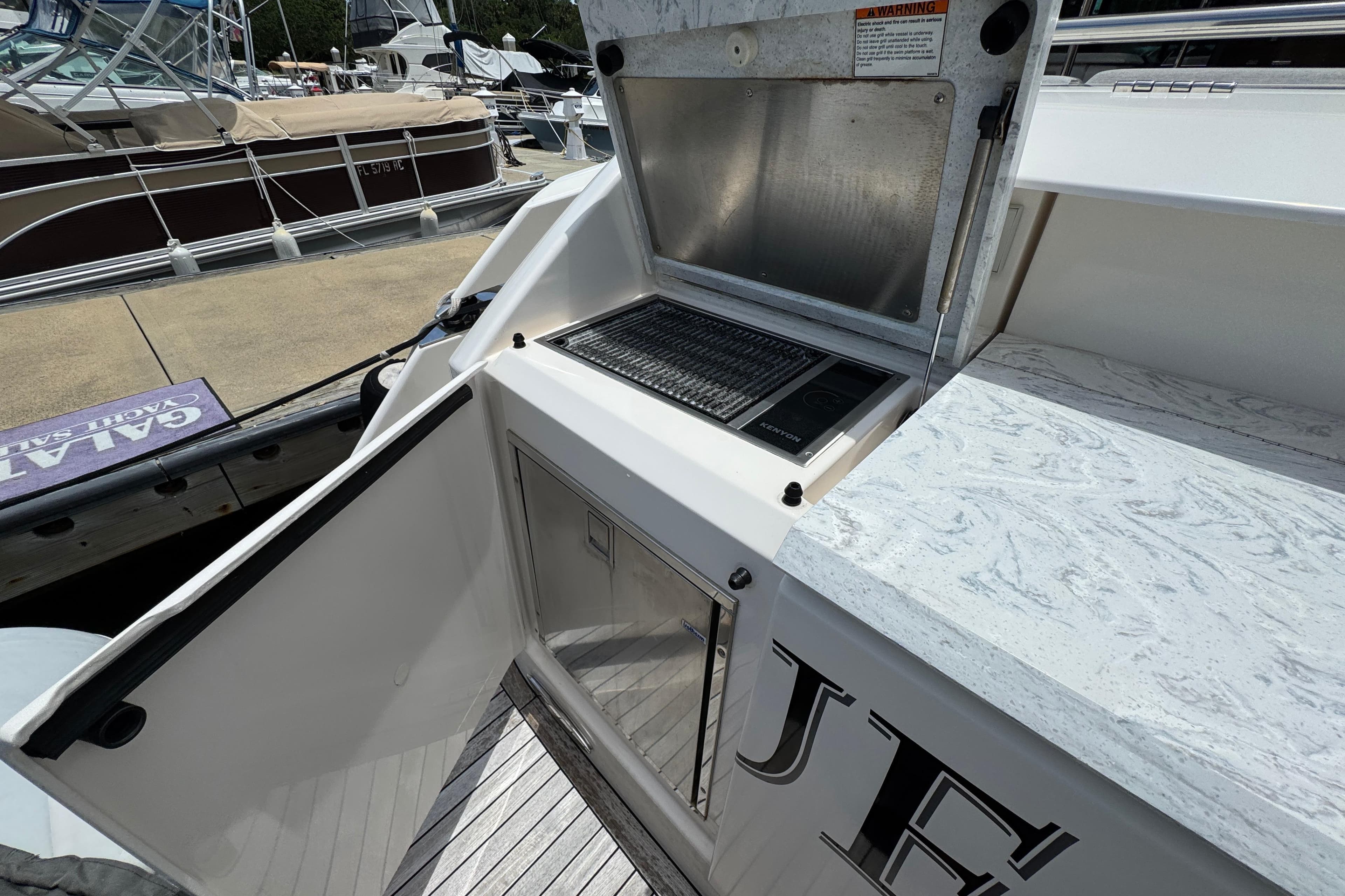 Outdoor kitchen on 2017 Tiara Yachts F53 Flybridge, featuring grill and storage.