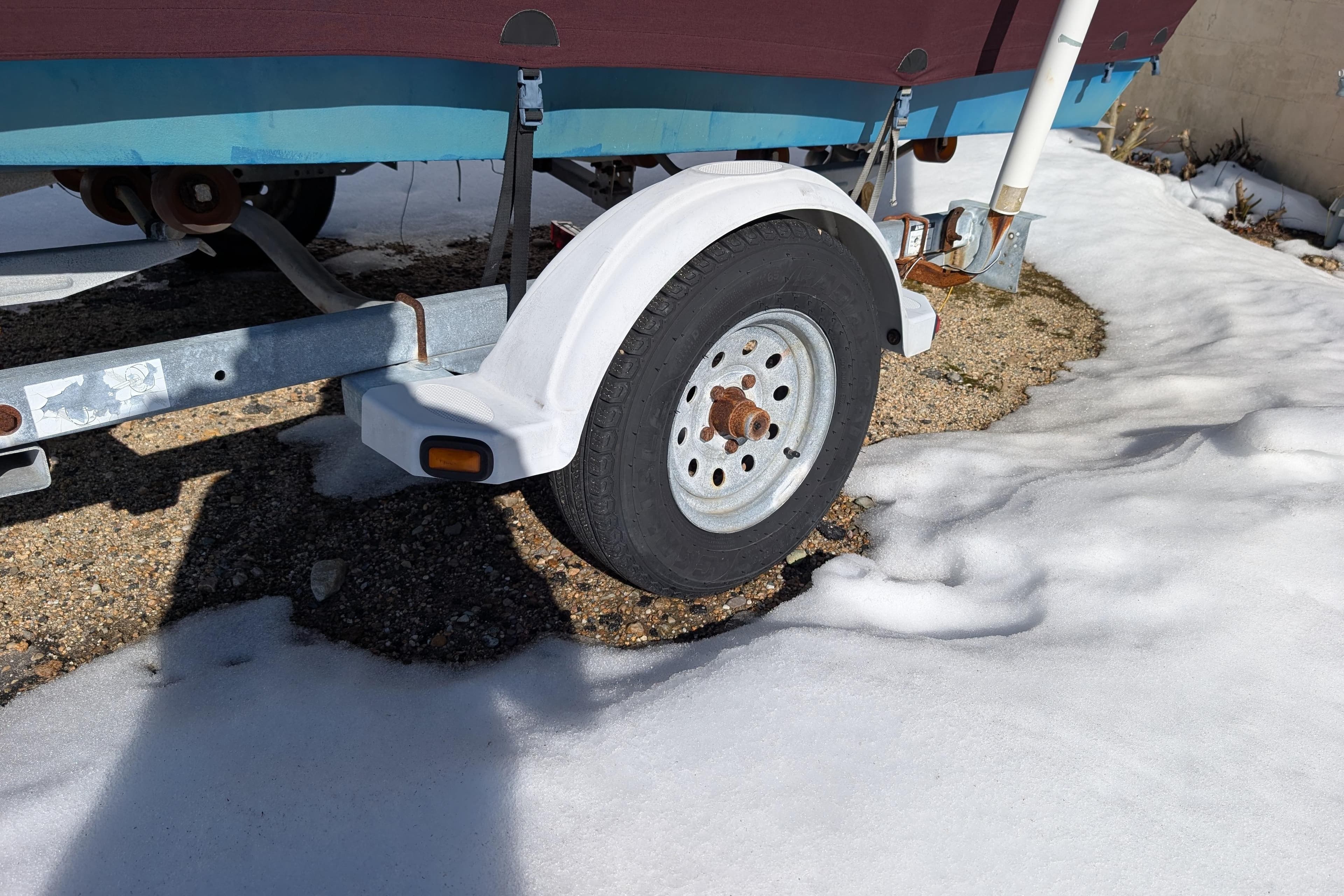 Trailer wheel of a 1988 Custom Skiff on snowy ground.