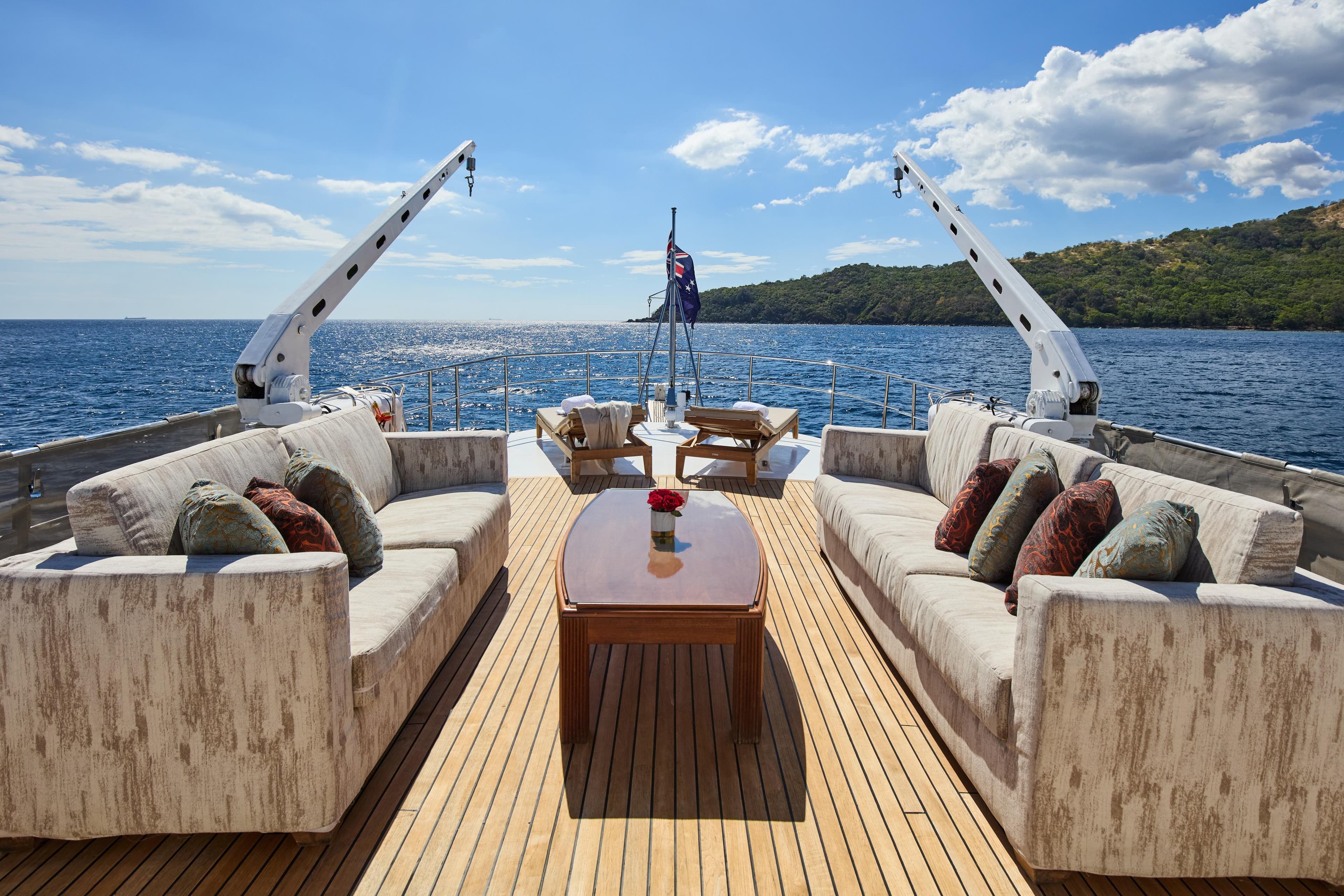 Luxurious deck of 1973 Benetti 26D yacht with elegant seating, ocean view, and clear skies.