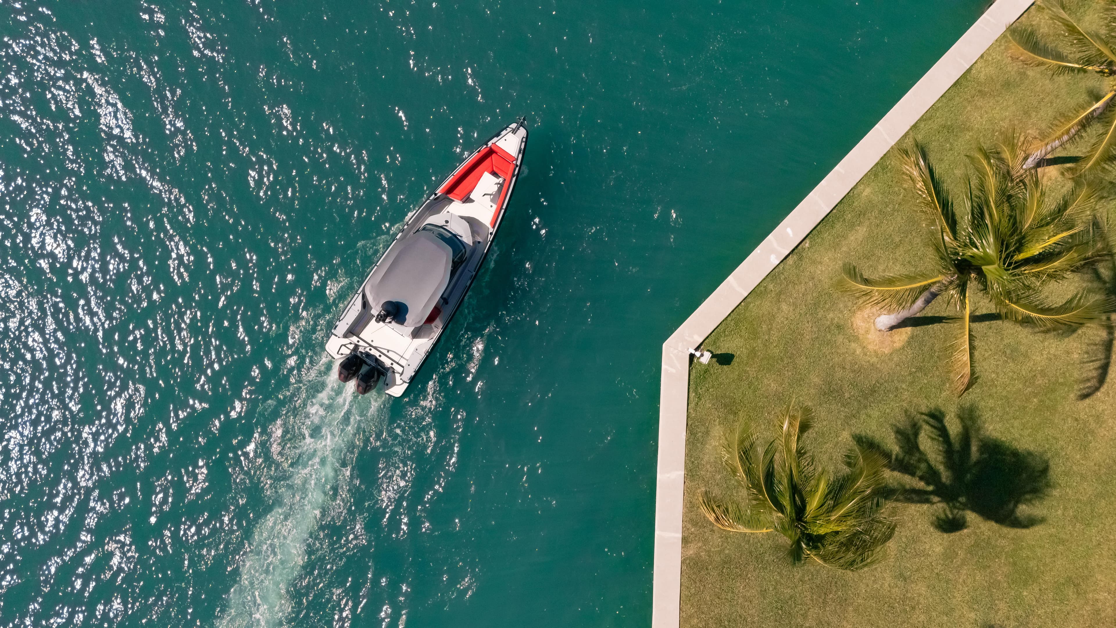 Aerial view of 2023 BRABUS Shadow 500 T-Top boat near a palm-lined shore.