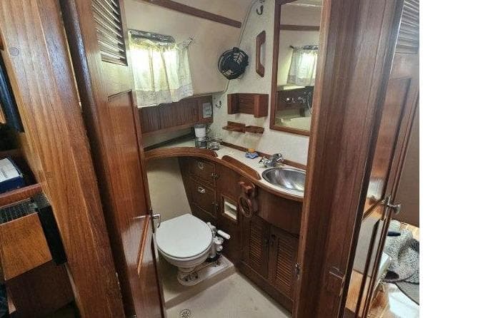 1999 Island Packet 350 yacht bathroom with wooden cabinetry, sink, and toilet.