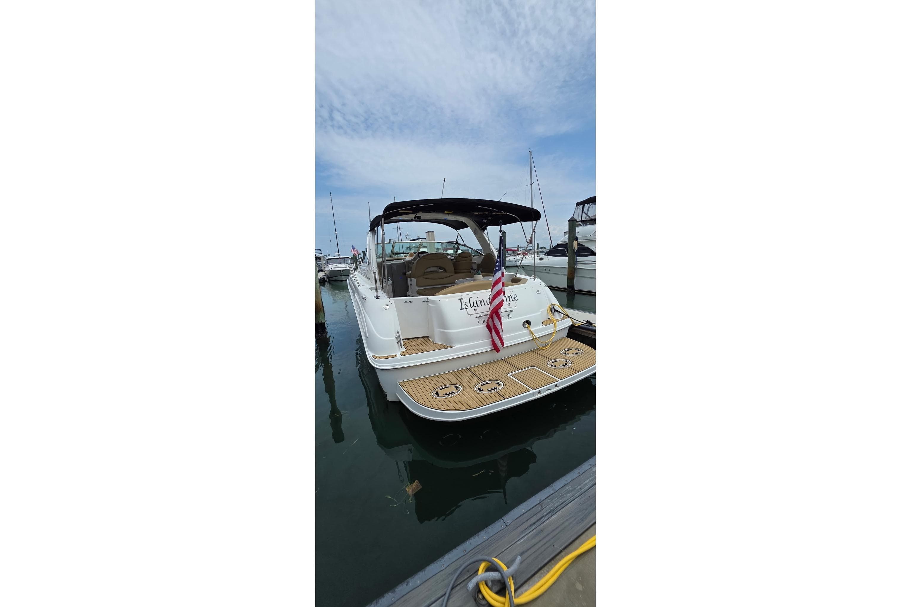 2002 Sea Ray 380 Sundancer docked, featuring a spacious deck and American flag.