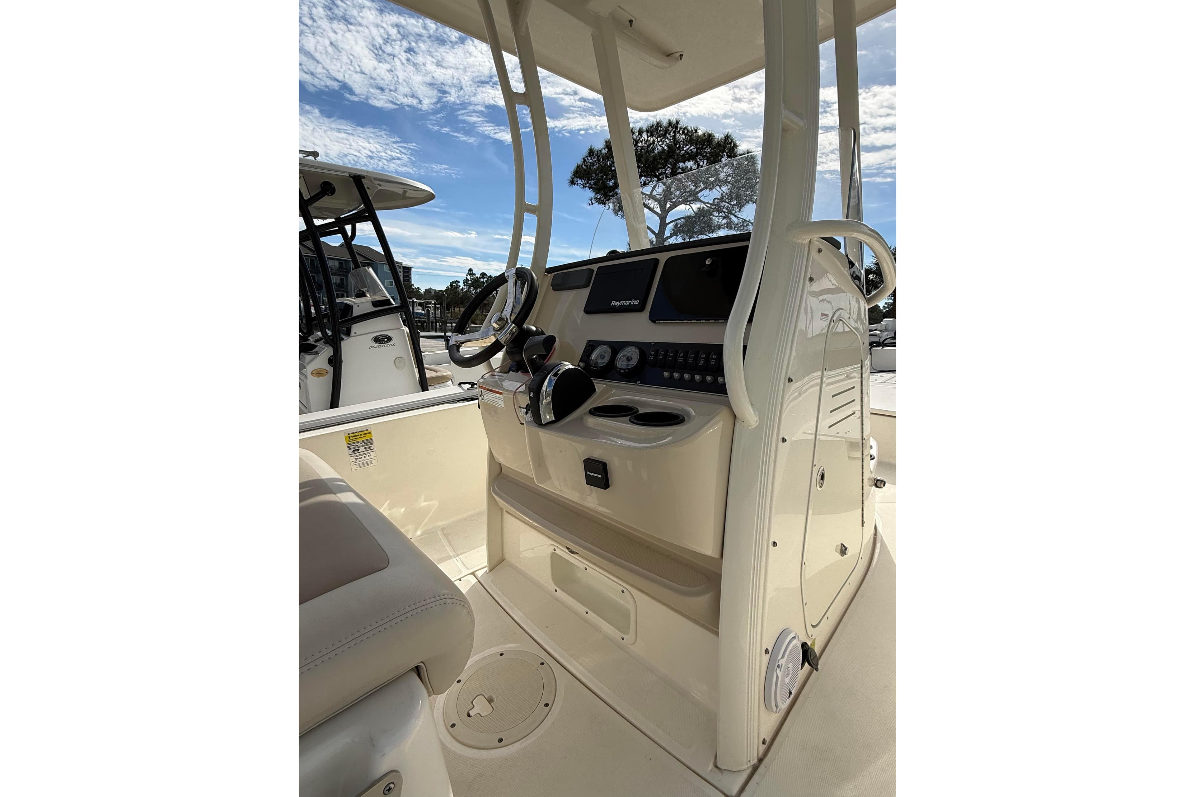 2020 Boston Whaler 240 Dauntless boat console with steering wheel and controls under a clear sky.