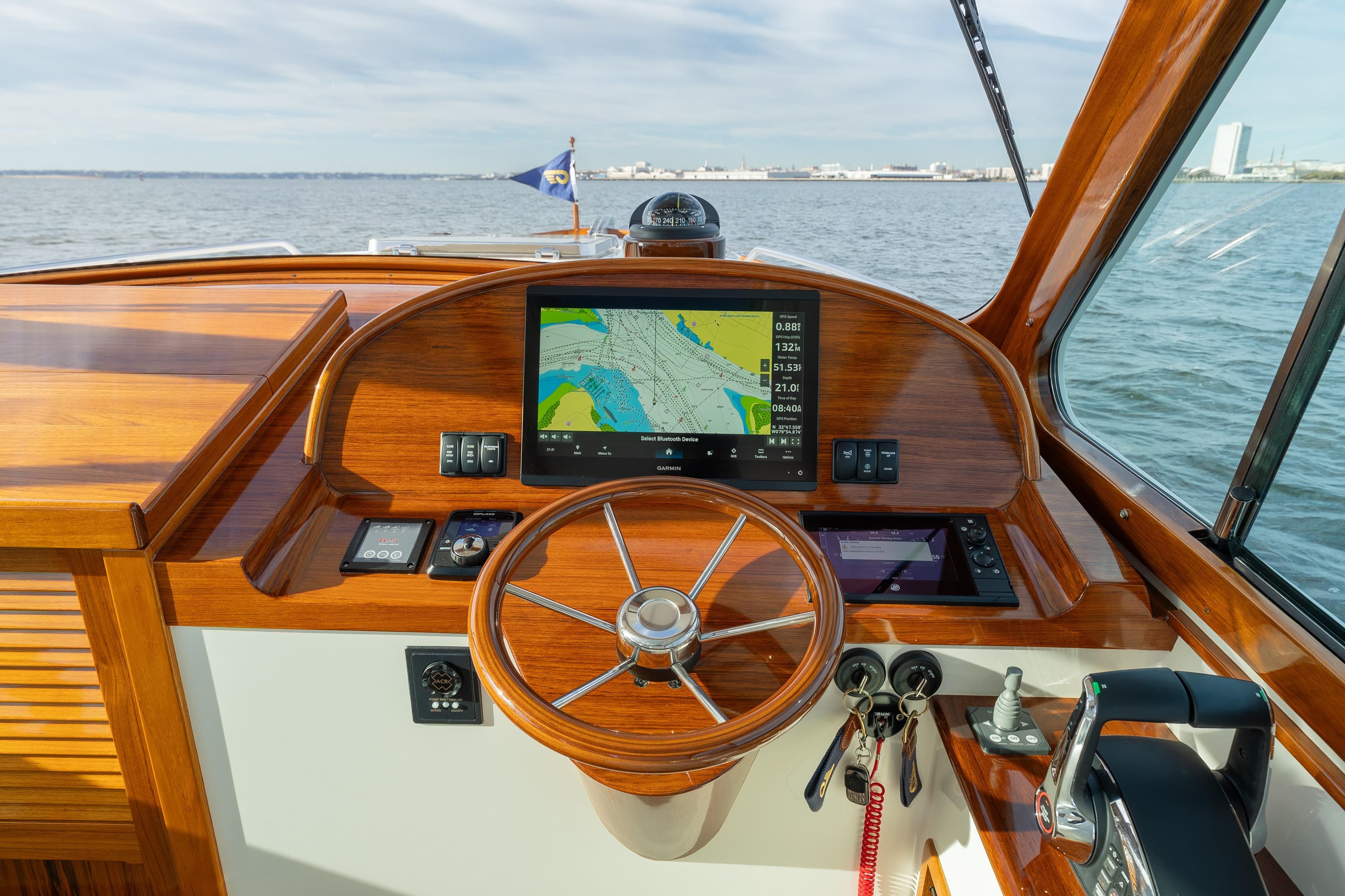 Helm of 2024 Hinckley 35 boat with navigation display and wooden finish.