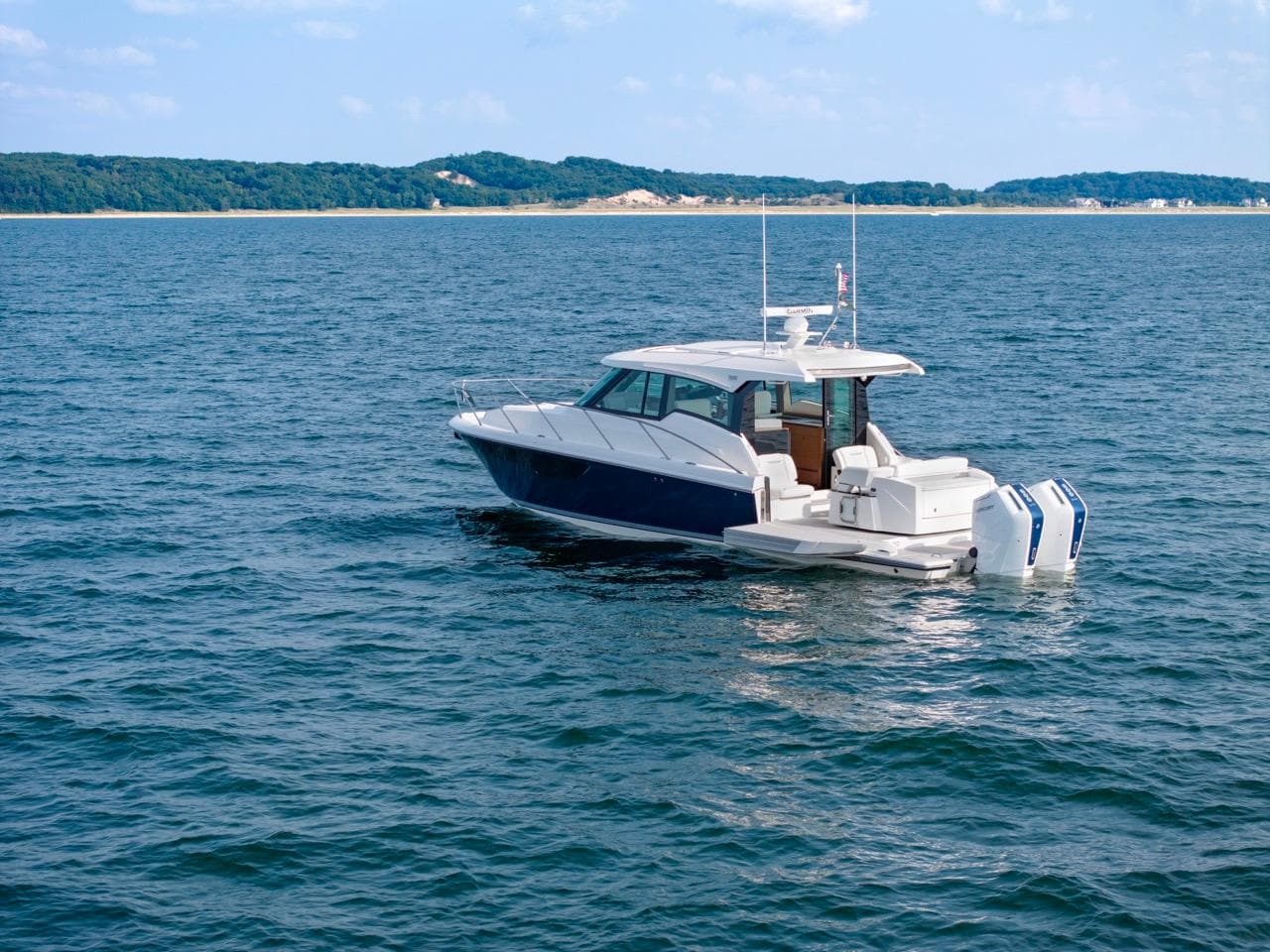 2025 Tiara Yachts 43 LE cruising on open water with scenic coastline in background.