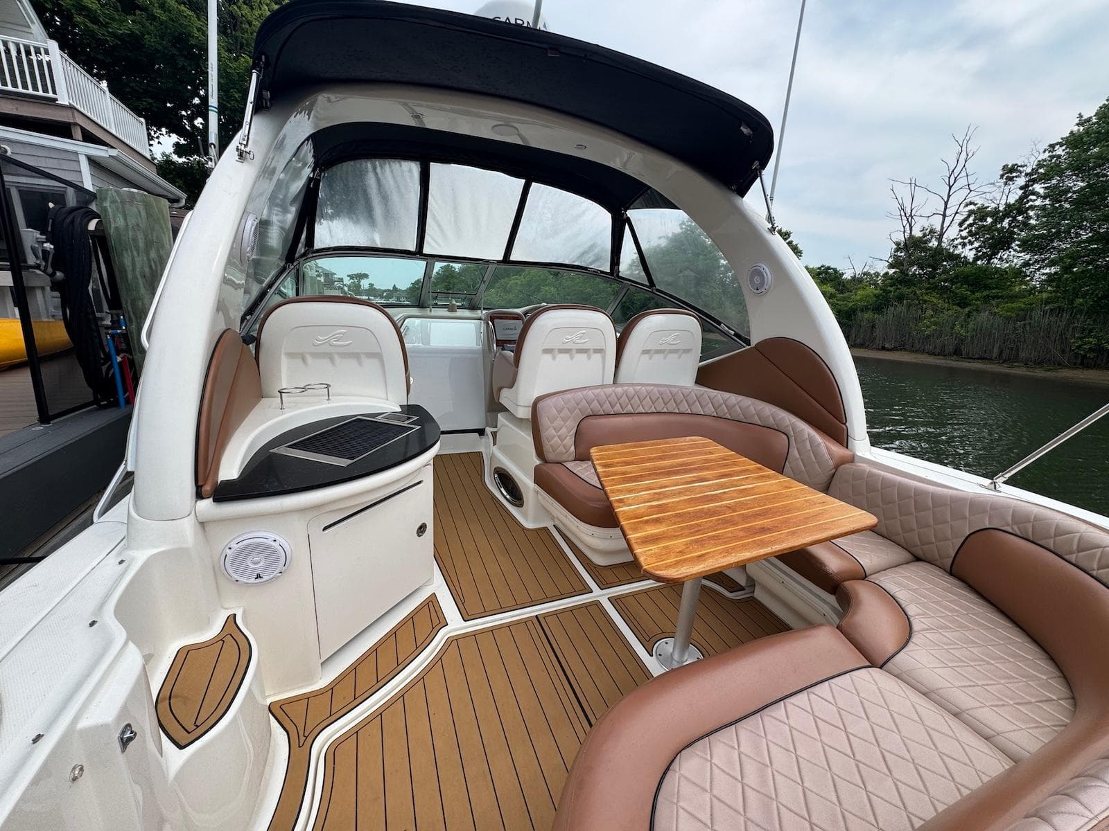 2003 Sea Ray 340 Sundancer interior with elegant seating and wooden table on deck.
