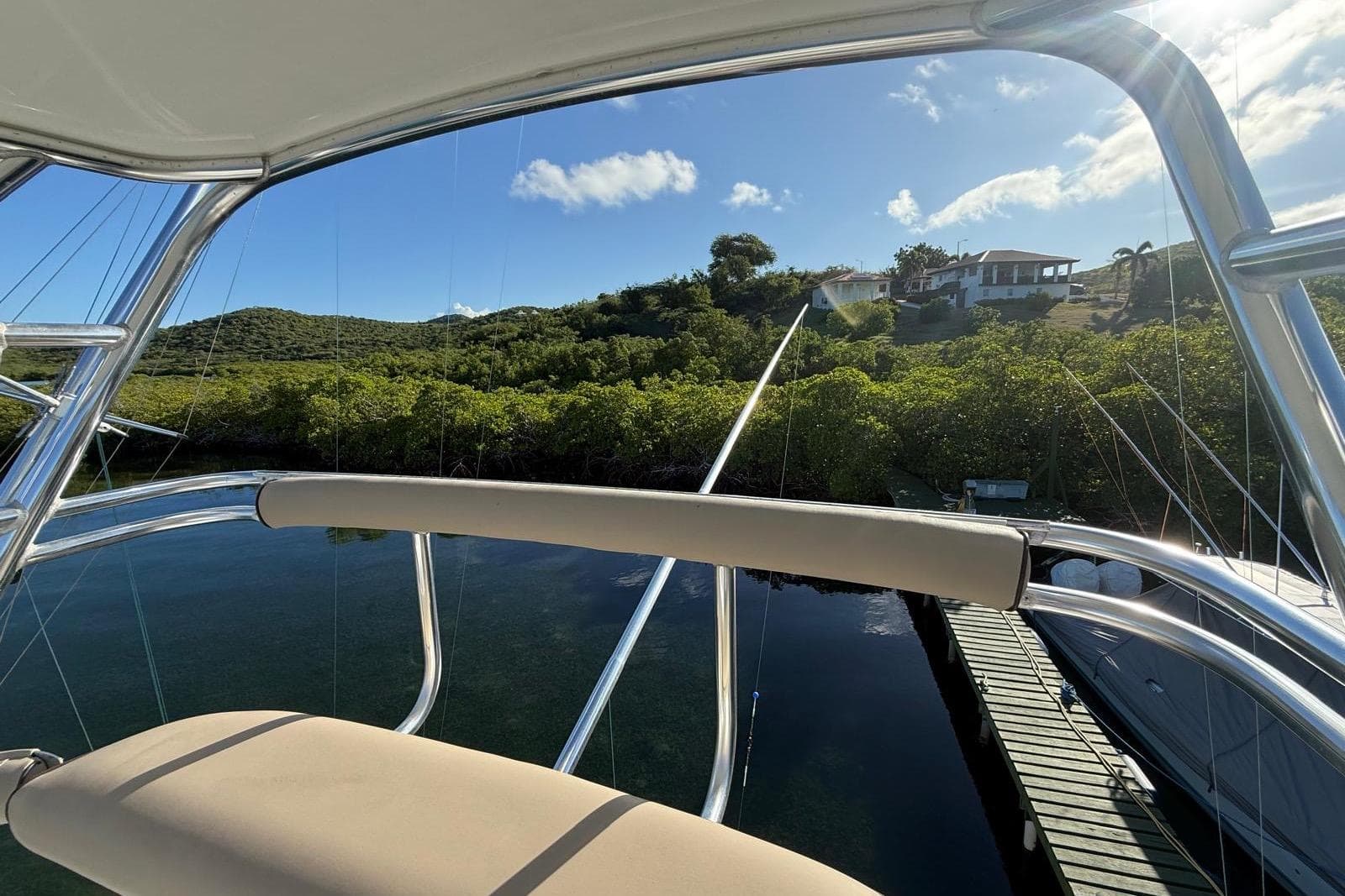 View from a 2003 Cabo 35 Express boat overlooking lush greenery and a dock.
